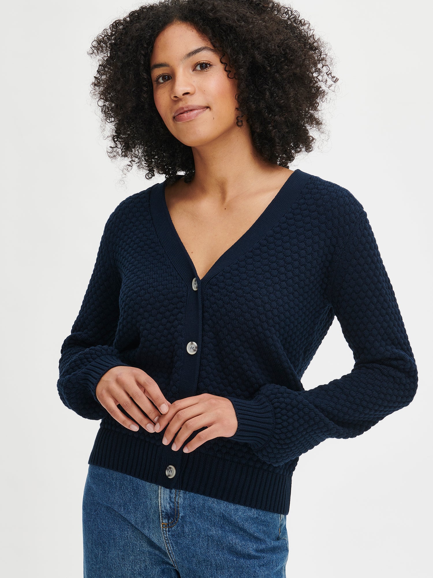 This women's KUMPU Knit Cardigan in dark blue features a structured texture. With its stylish and comfortable cotton material, it's the perfect addition to any everyday outfit. Worn by a model in size S from the front.