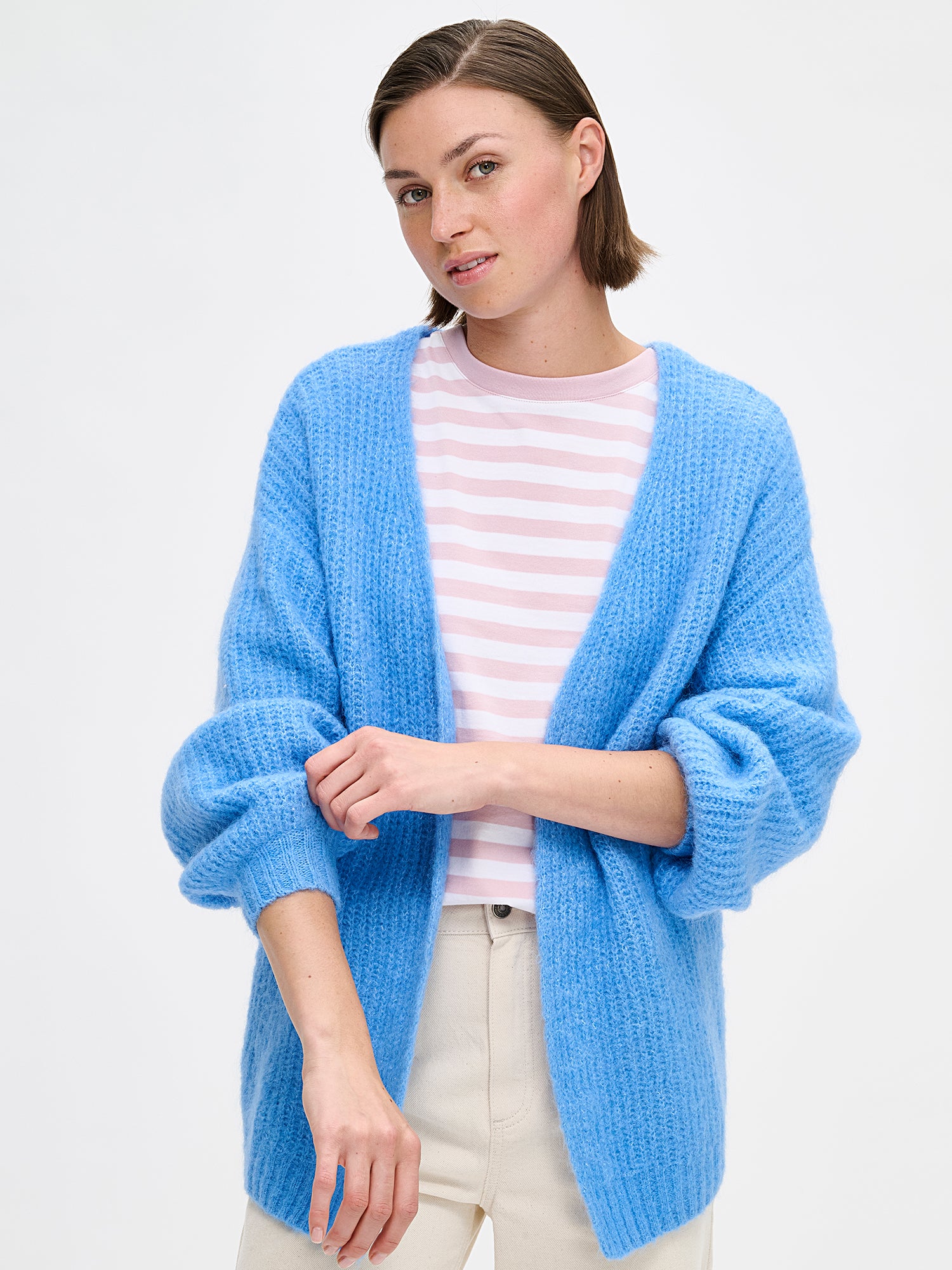 Women's long-sleeved KARAMELLI Cardigan in blue shade, knitted in a fitted shape. Made of a blend of certified mohair, certified wool, polyamide, and elastane. Pictured on a model with jeans close-up.