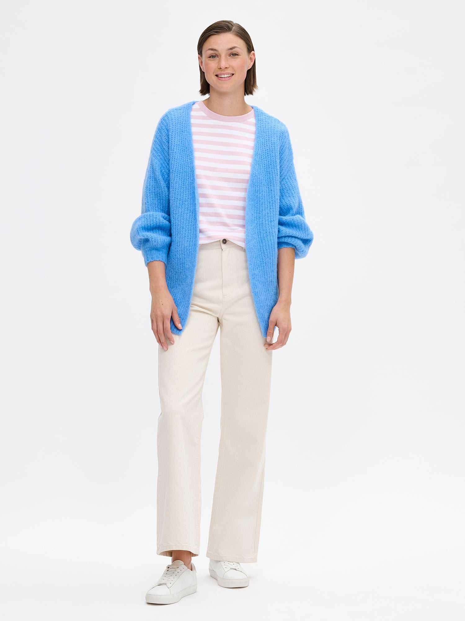 Women's long-sleeved KARAMELLI Cardigan in blue shade, knitted in a fitted shape. Made of a blend of certified mohair, certified wool, polyamide, and elastane. Pictured on a model with jeans.