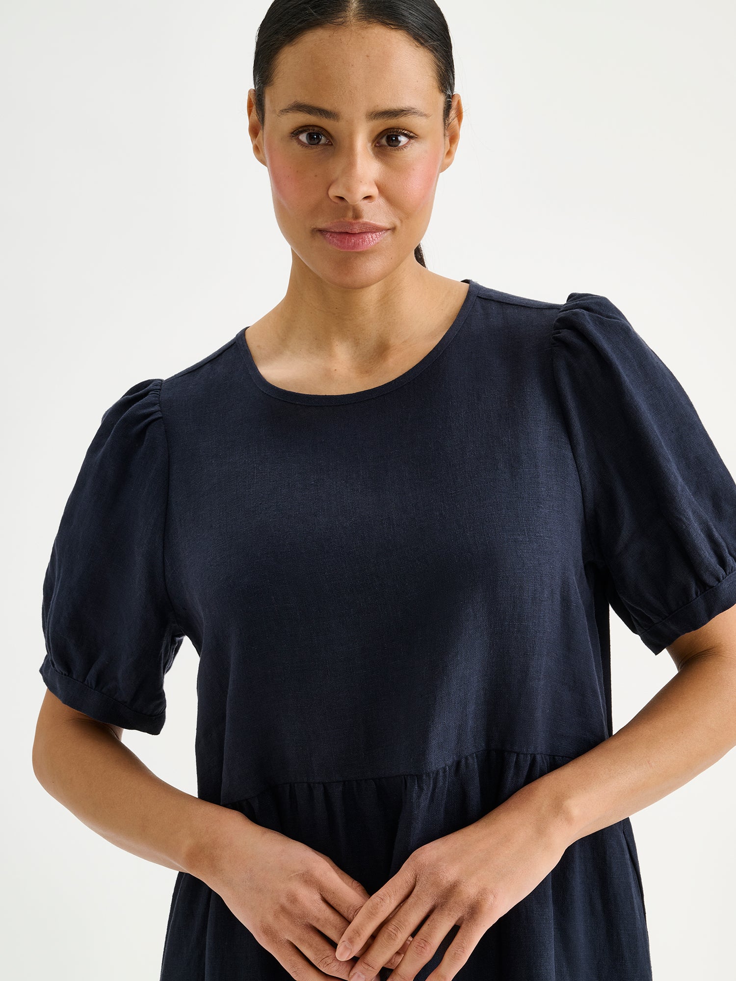 Nanso sarastus dark blue linen dress with voluminous frill layers and short puff sleeves on a model, close-up.