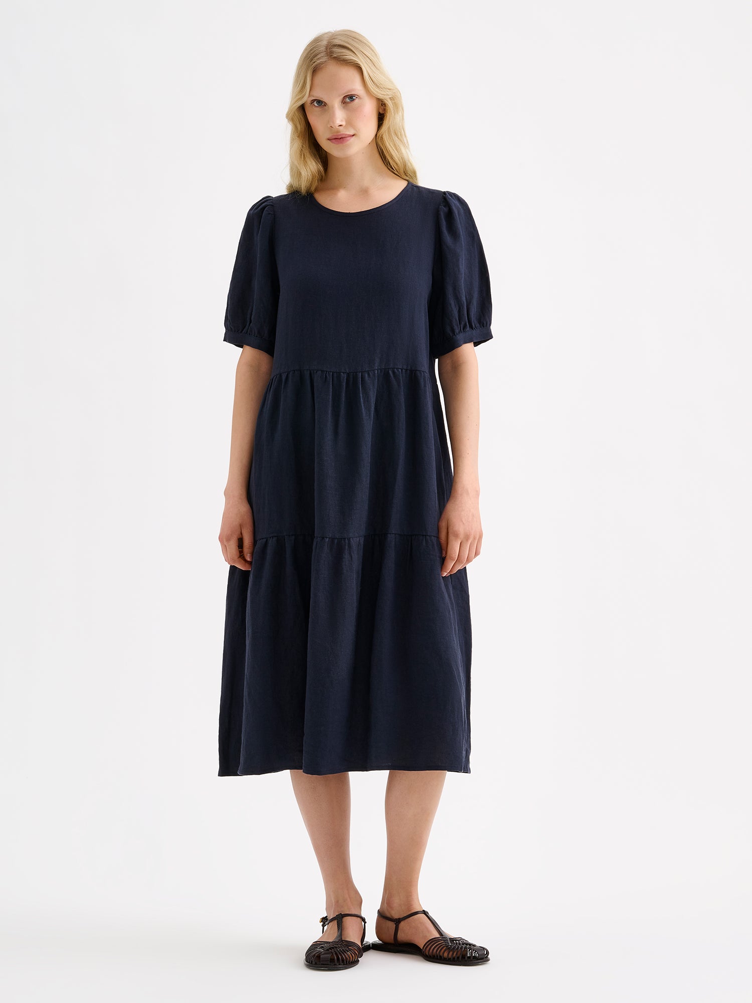 Nanso women's beautiful dark blue Sarastus midi linen dress features voluminous frill layers and short puff sleeves on a model 