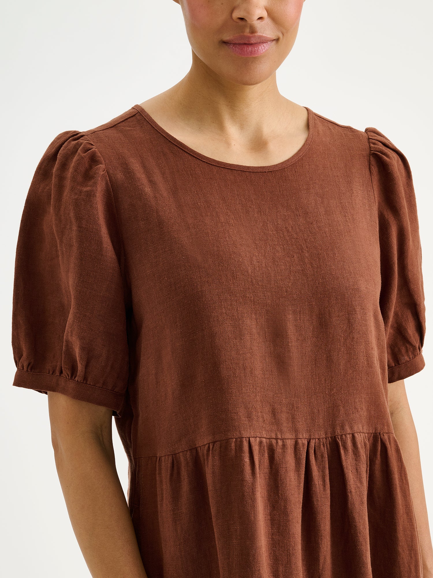 Nanso women's beautiful brown Sarastus midi linen dress features voluminous frill layers and short puff sleeves on a model, close-up.