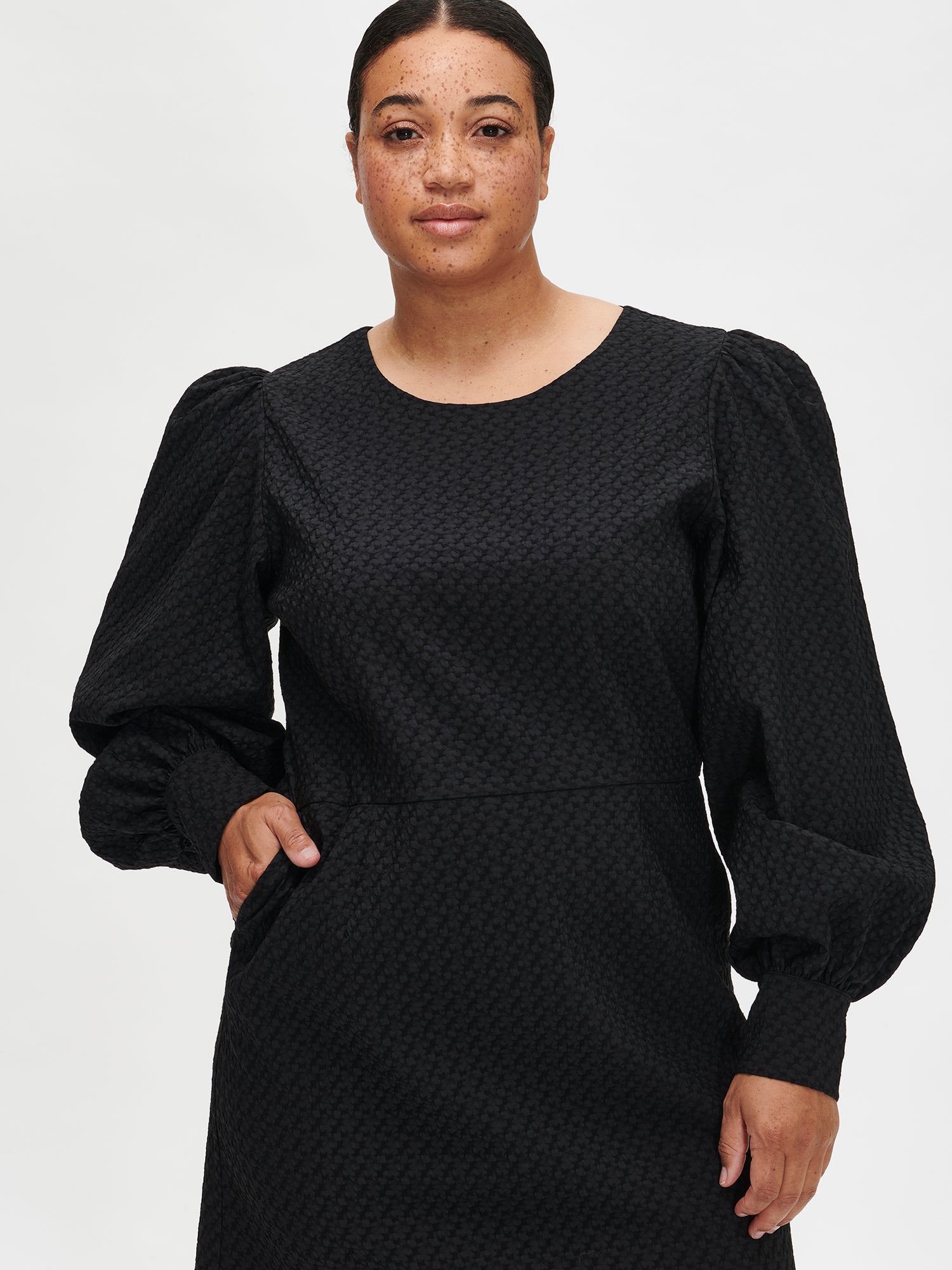 Nanso's elegant black Reliefi dress. On a model in size 46, front close-up