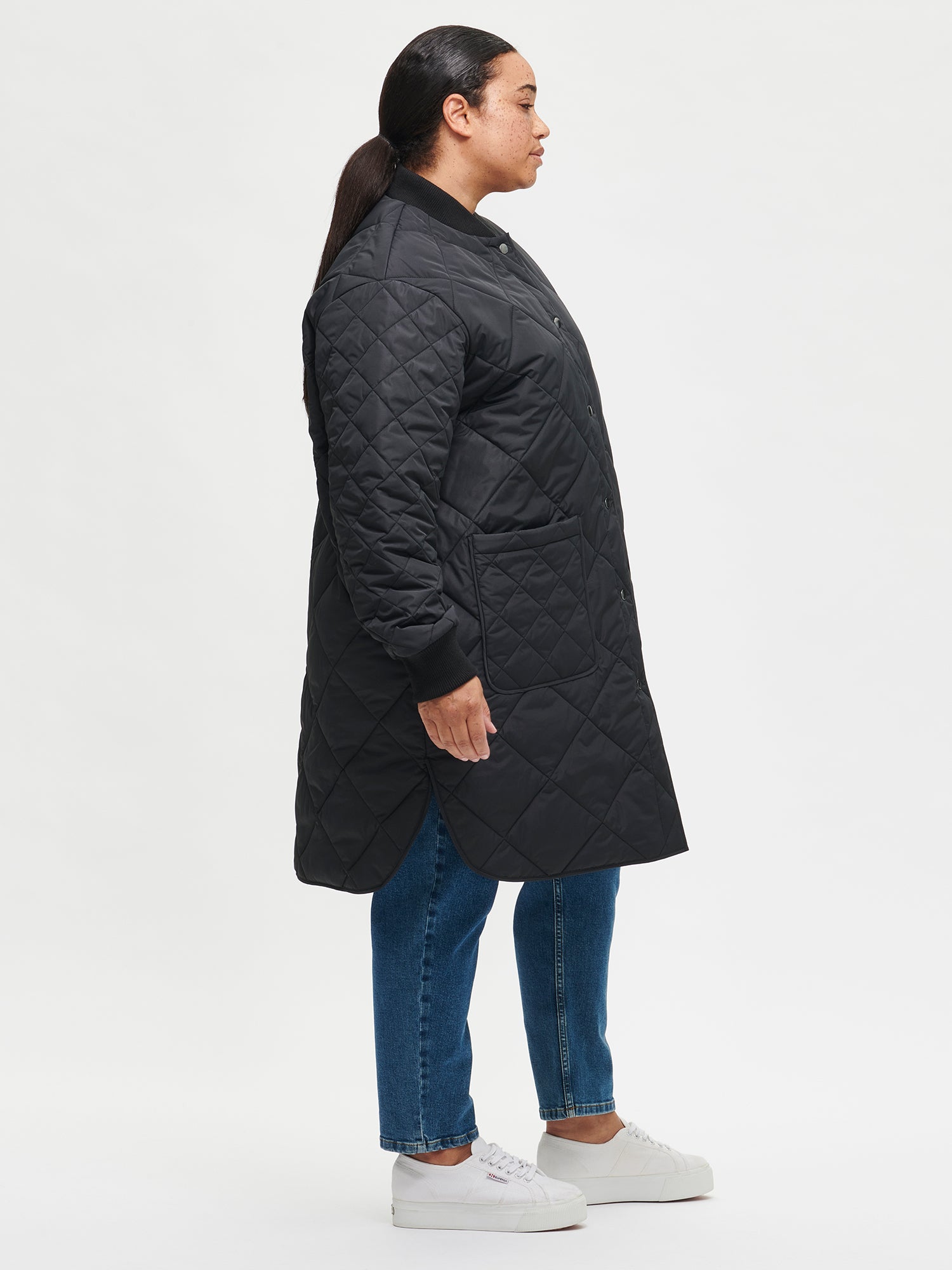 Nanso women's casual black Midi quilted coat on a model with jeans from the side angle
