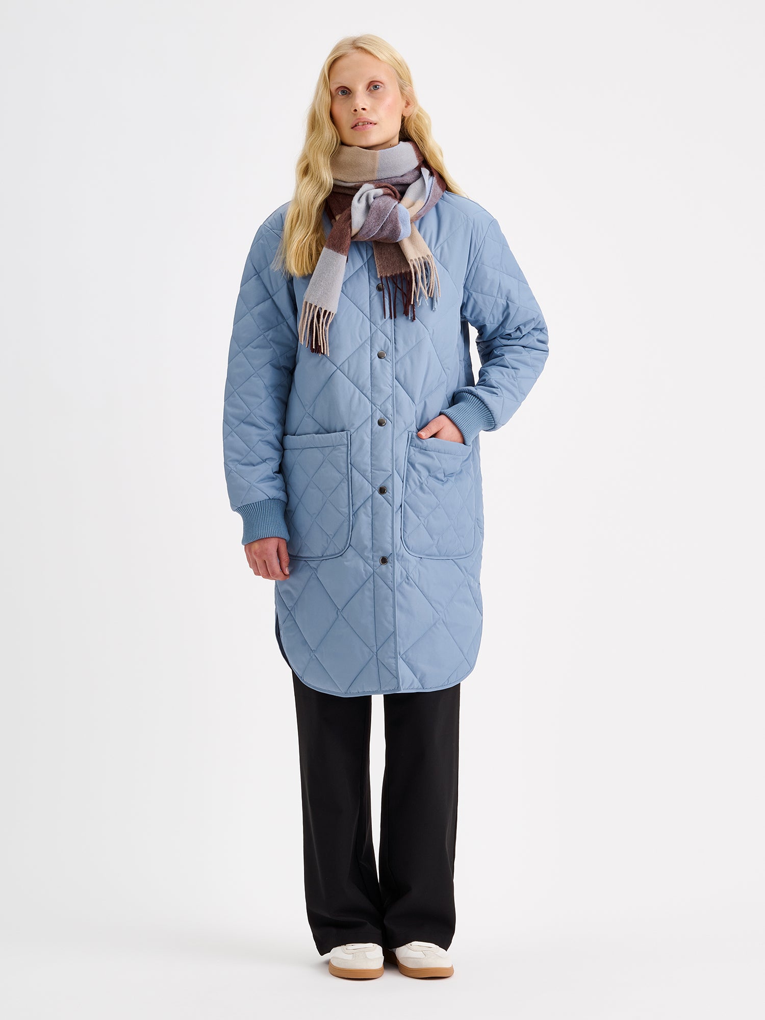 Nanso women's casual Midi quilted coat in smoky blue on a model with a wool scarf and black jeans.