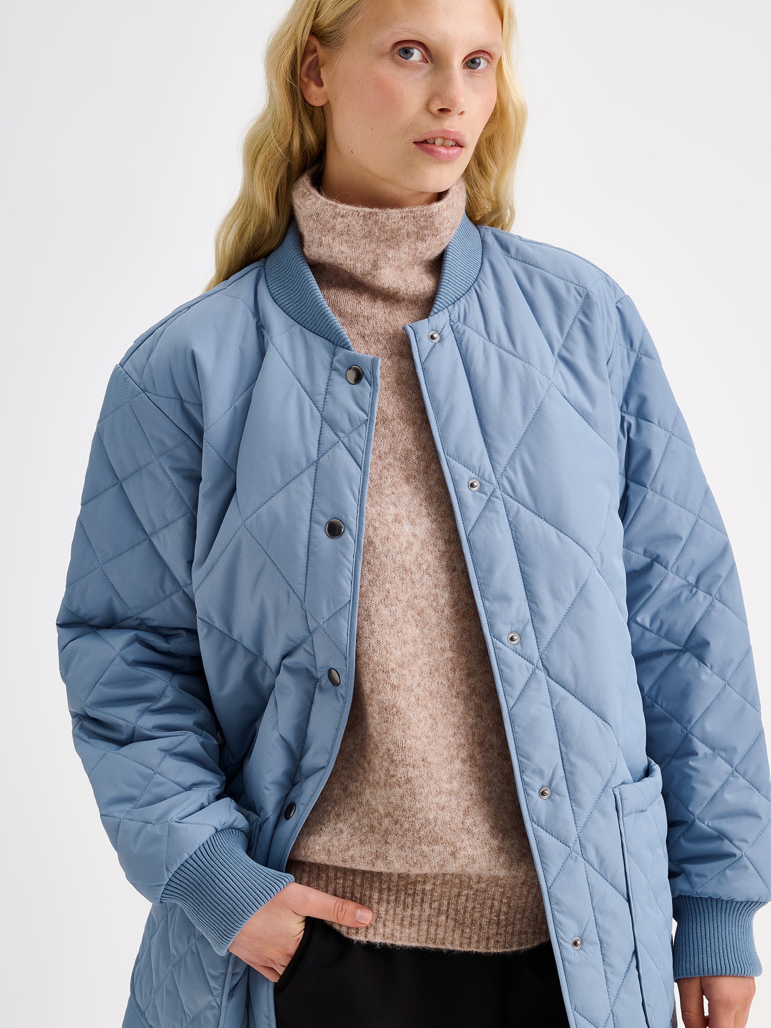 Nanso women's casual Midi quilted coat in smoky blue on a model with a beige sweater.