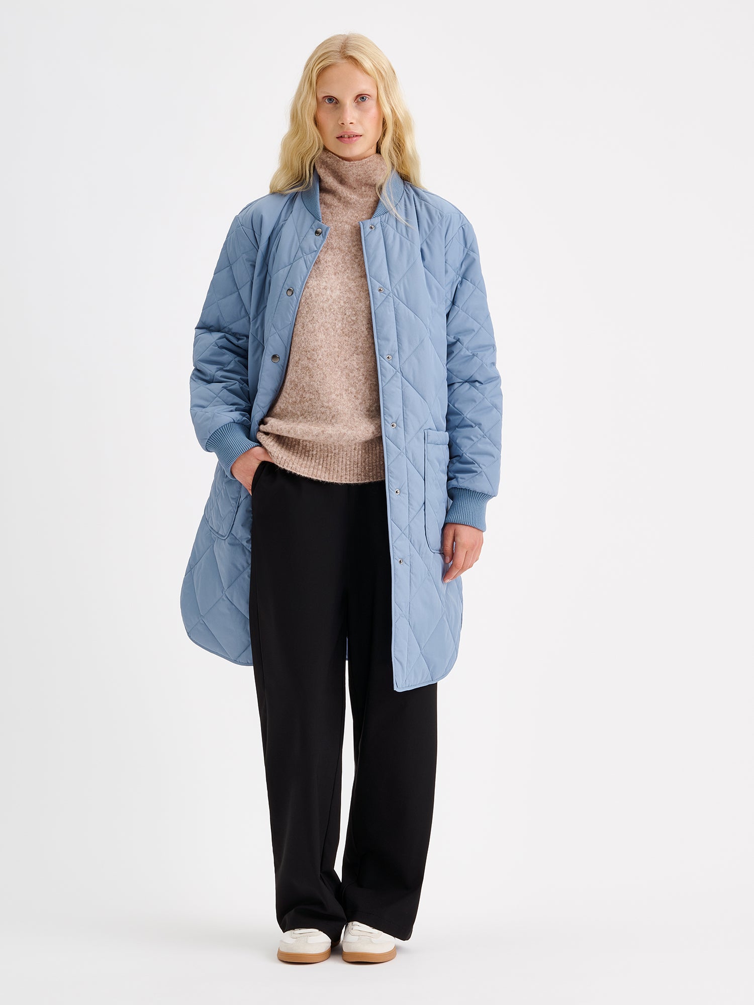 Nanso women's casual Midi quilted coat in smoky blue on a model with a beige sweater and black jeans.