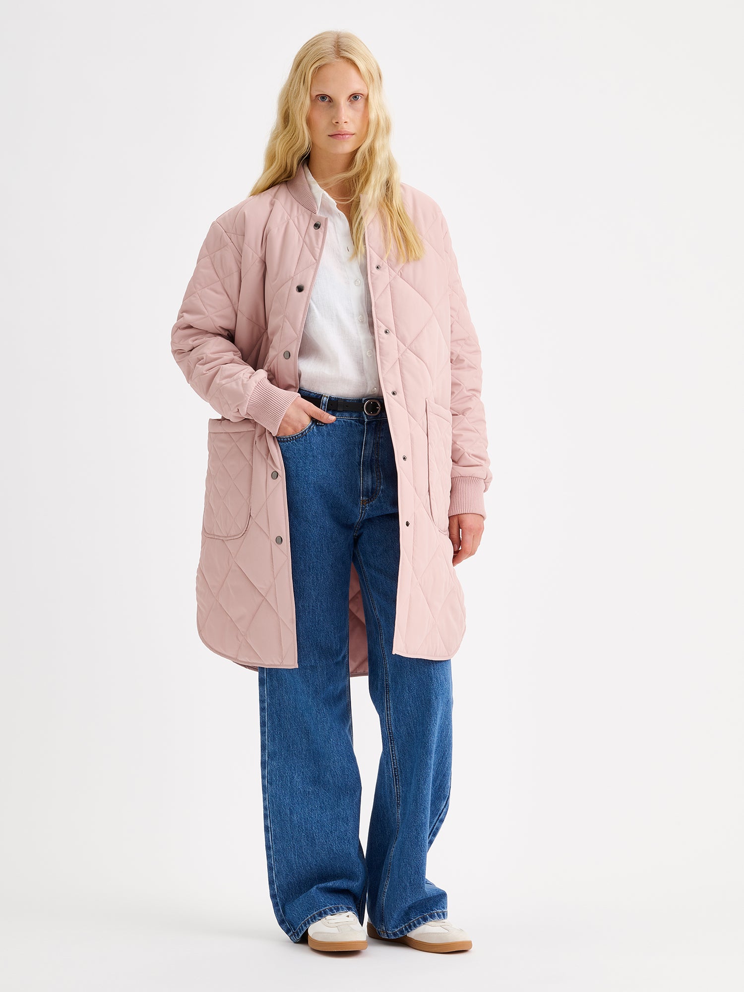 Nanso women's casual Midi quilted coat in dark blue features lightweight padding, ribbed knit detailing at the neckline and cuffs, snap closures and front pockets. Pictured on a model, coat opened.