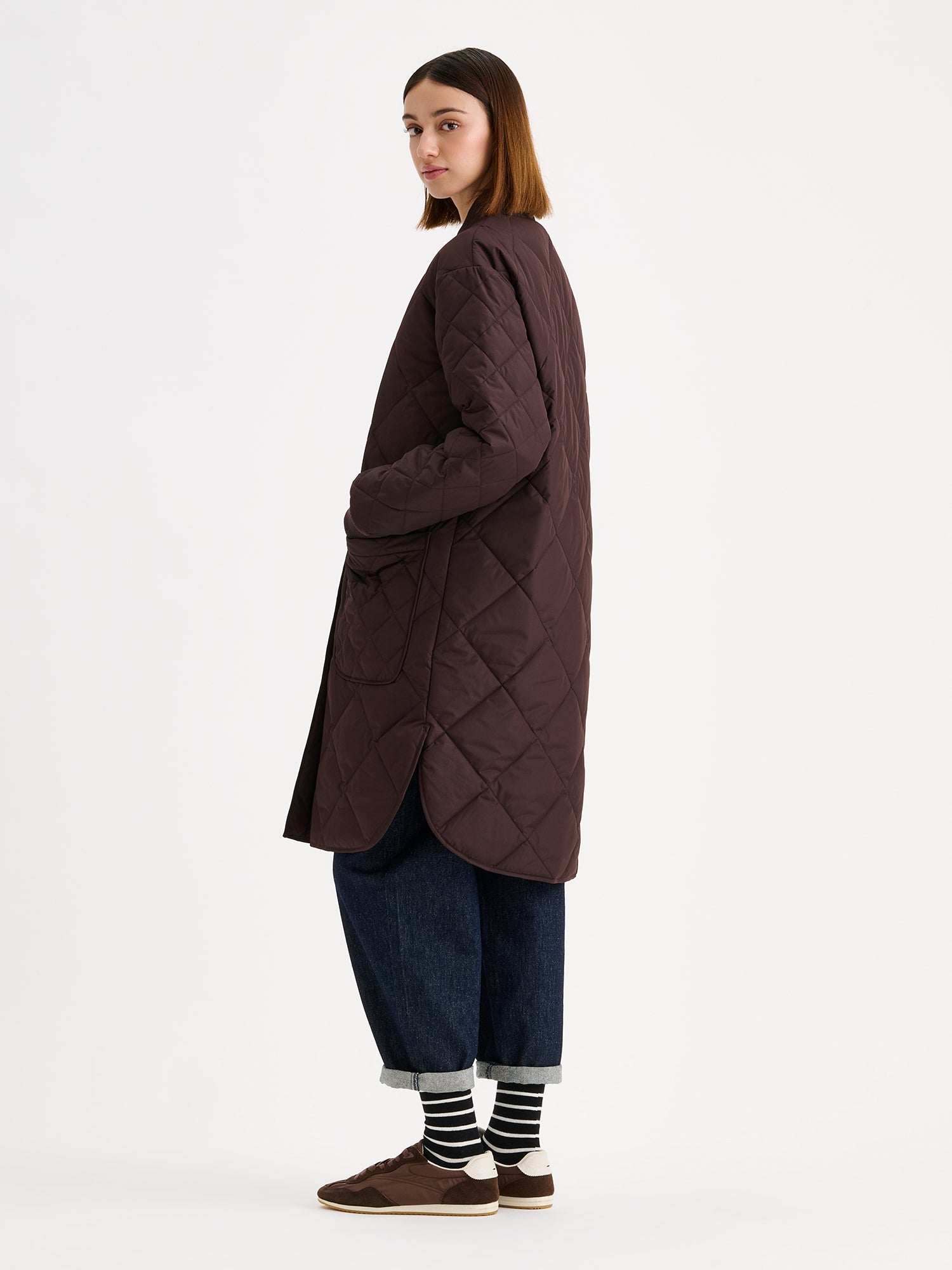 Nanso women's casual Midi quilted coat in brown on a brunette model with blue jeans from the side angle