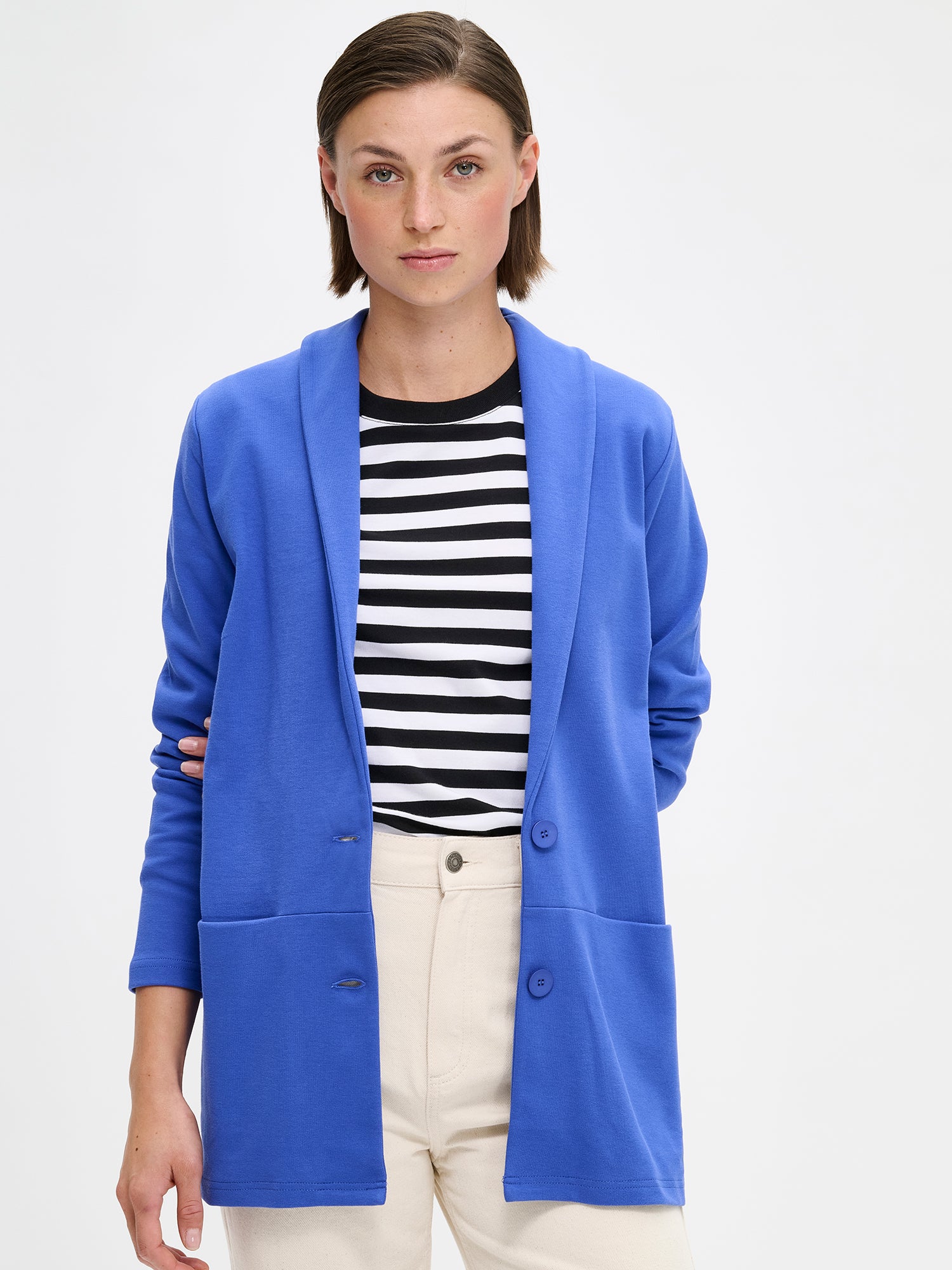 Nanso women's blue Leija jacket features a collar, front button closure, and bust darts. Sleeves are full-length. The front horizontal seam has embedded pockets. Pictured on a model, close-up.