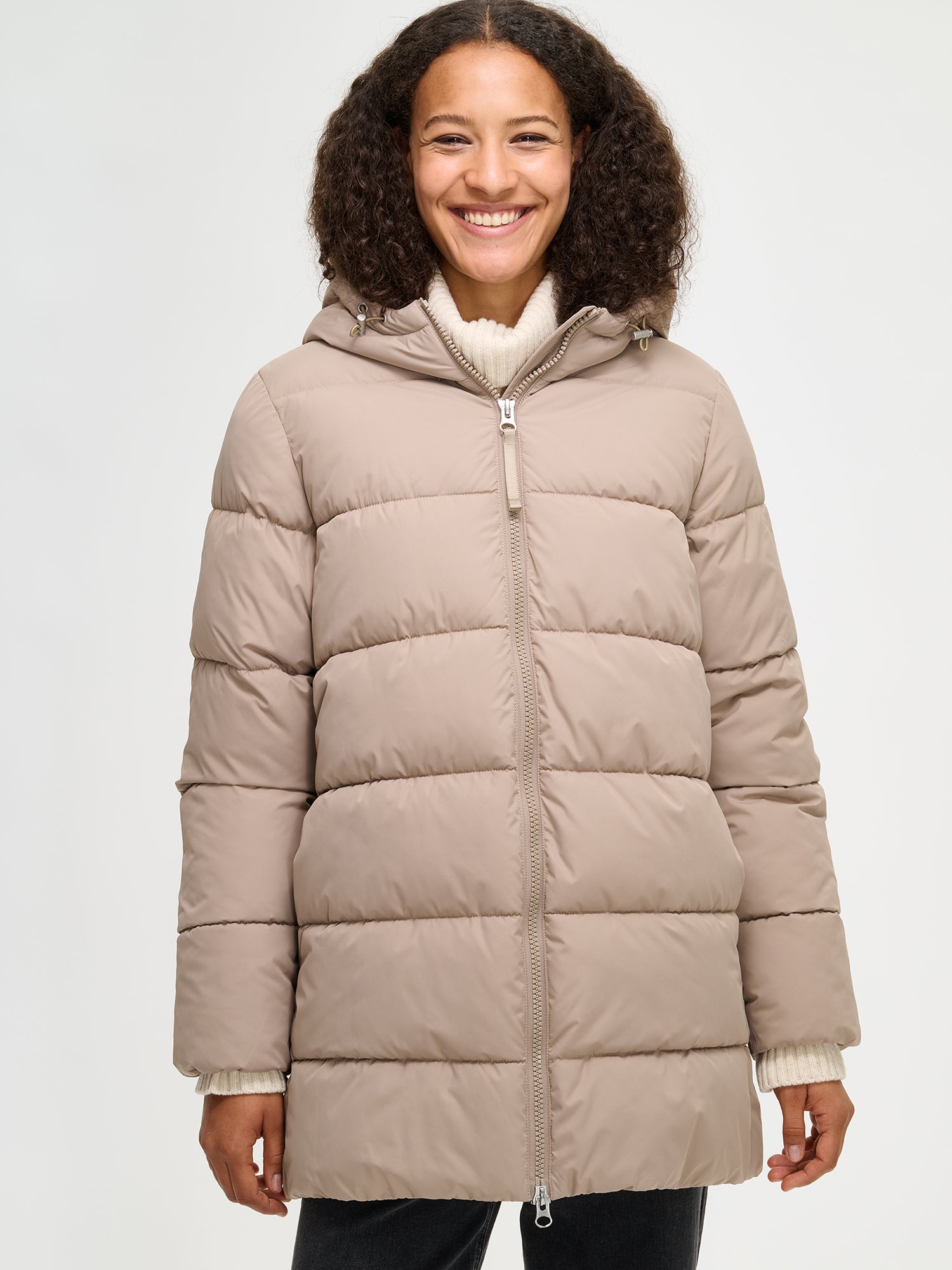 The beige Lumi padded coat provides warmth with its soft, lightweight padding and generous fit. From the front, worn by a model in size S.