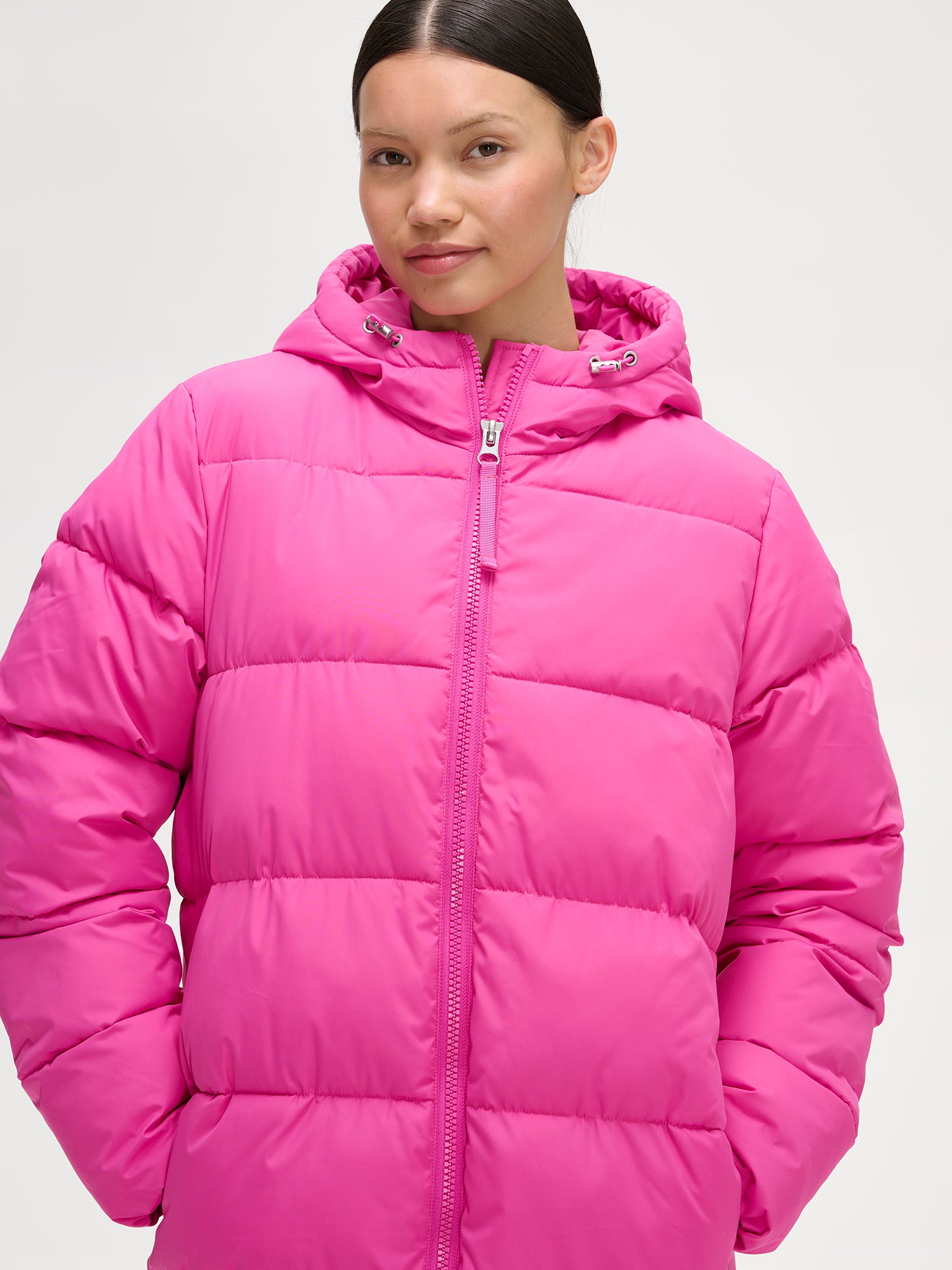 Nanso women´s Lumi Long Pink Puffer Coat in pink offers cozy warmth with its lightweight, puffy insulation. Worn by a model.