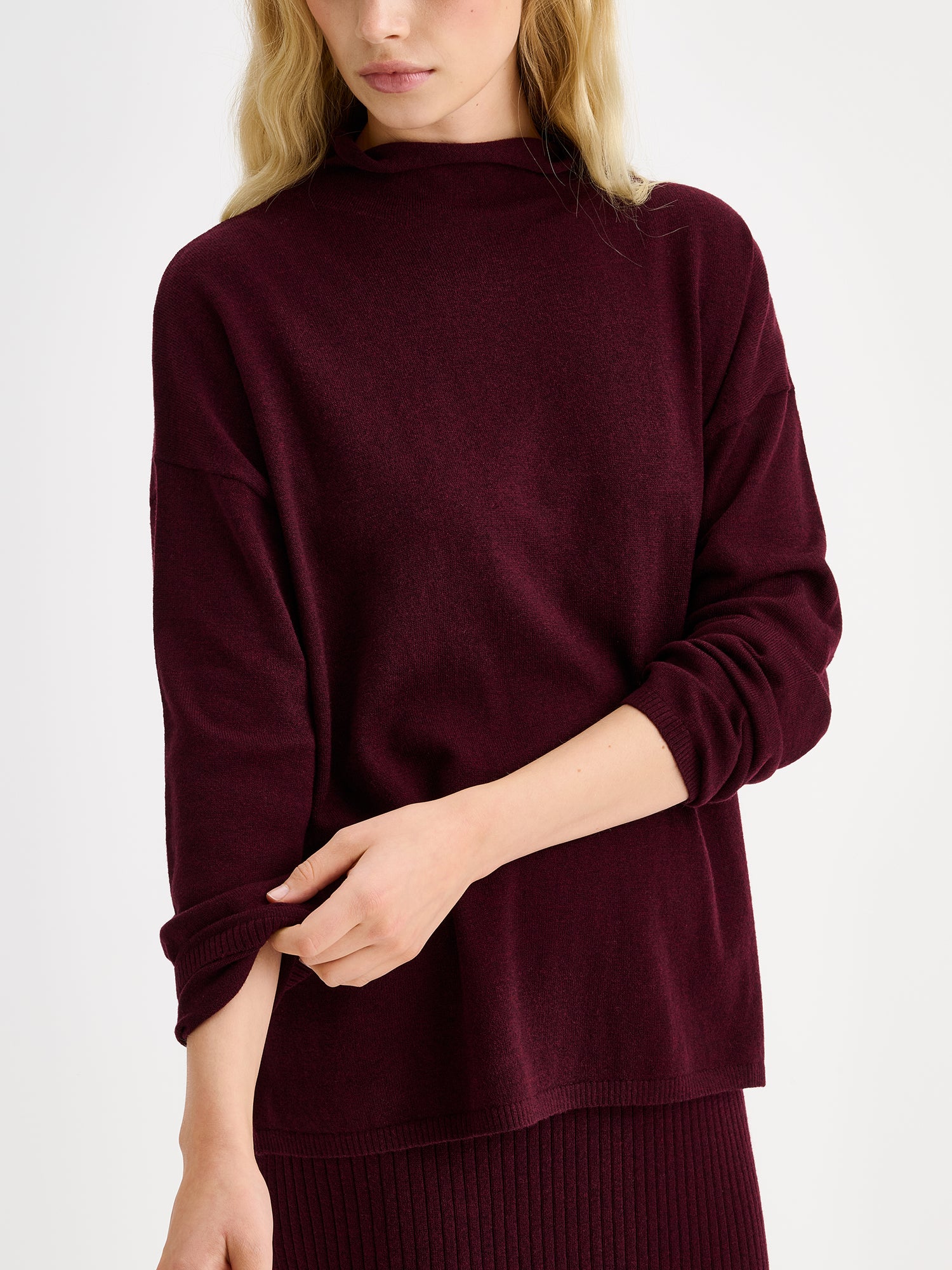 Nanso women´s burgundy Villis long-sleeved sweater on a model with a matching skirt, close-up