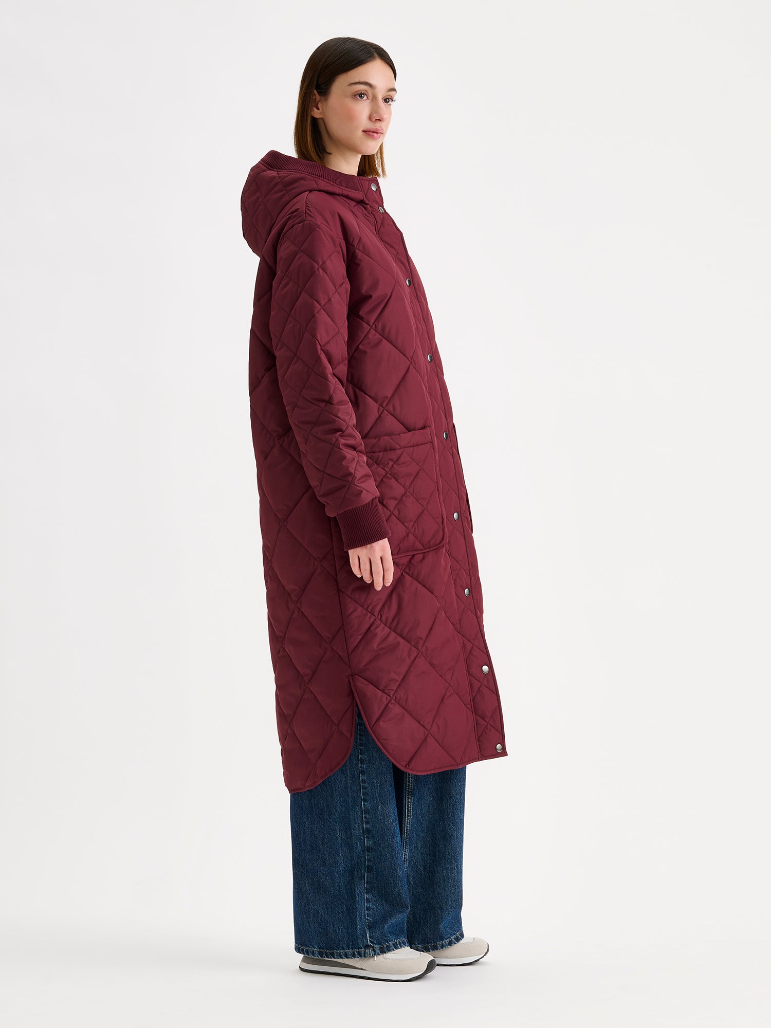 Nanso women's casual winered Maxi quilted coat with light padding and a cozy hood, on a model with blue jeans from the side angle