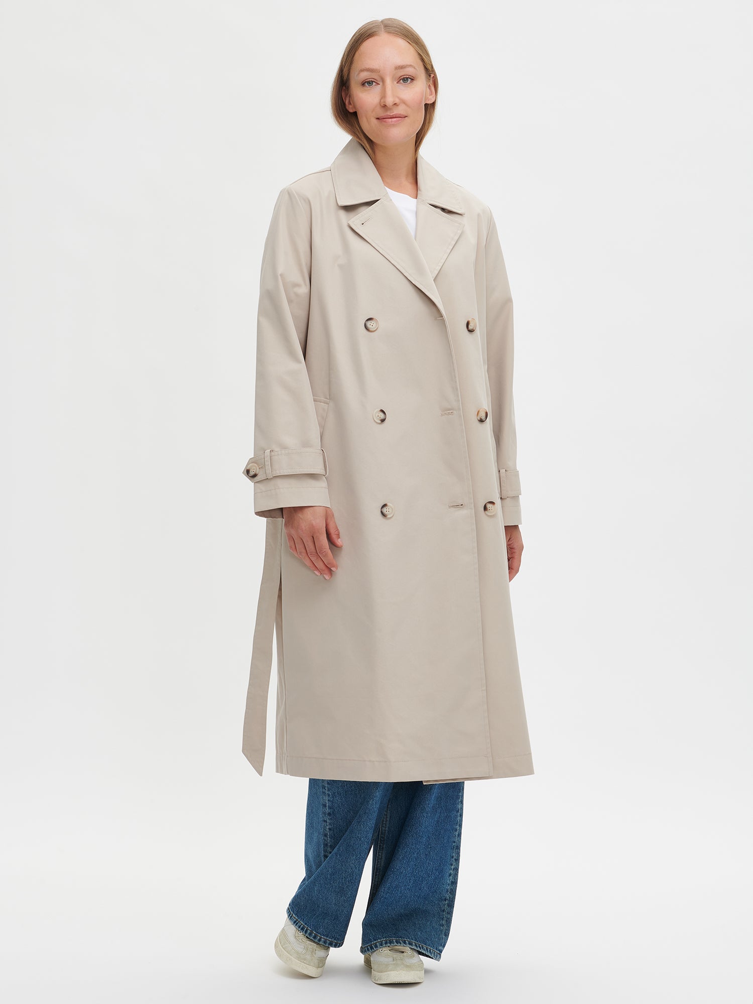 A timeless Beige trench coat on a model with blue jeans