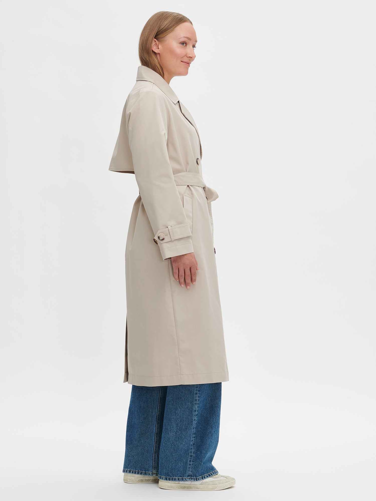 A timeless Beige trench coat on a model with blue jeans