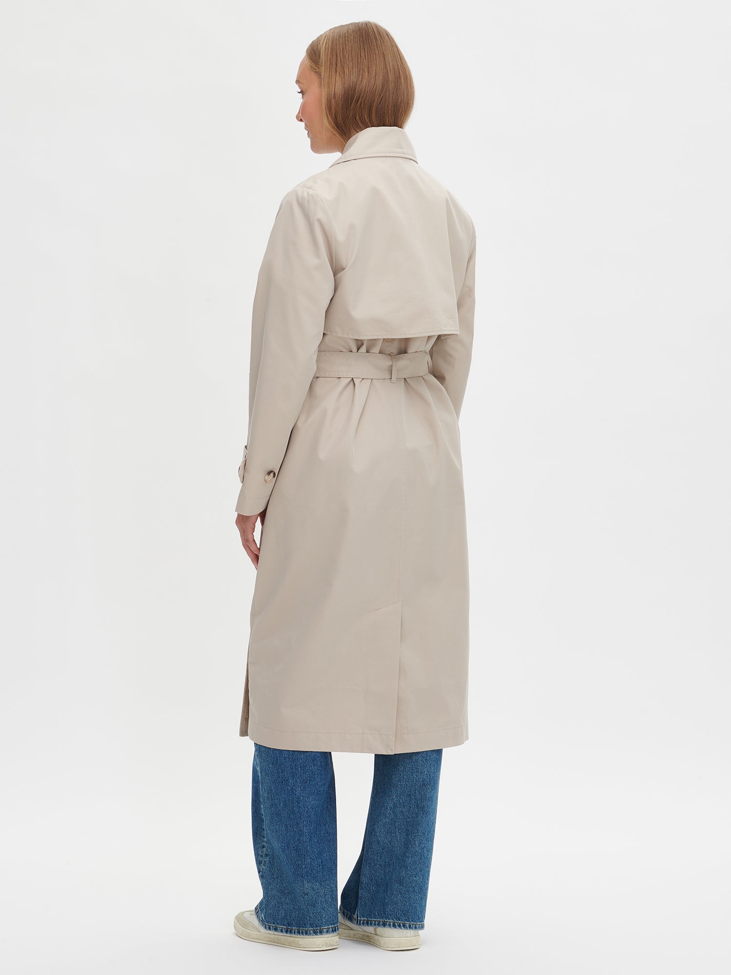 A timeless Beige trench coat on a model with blue jeans
