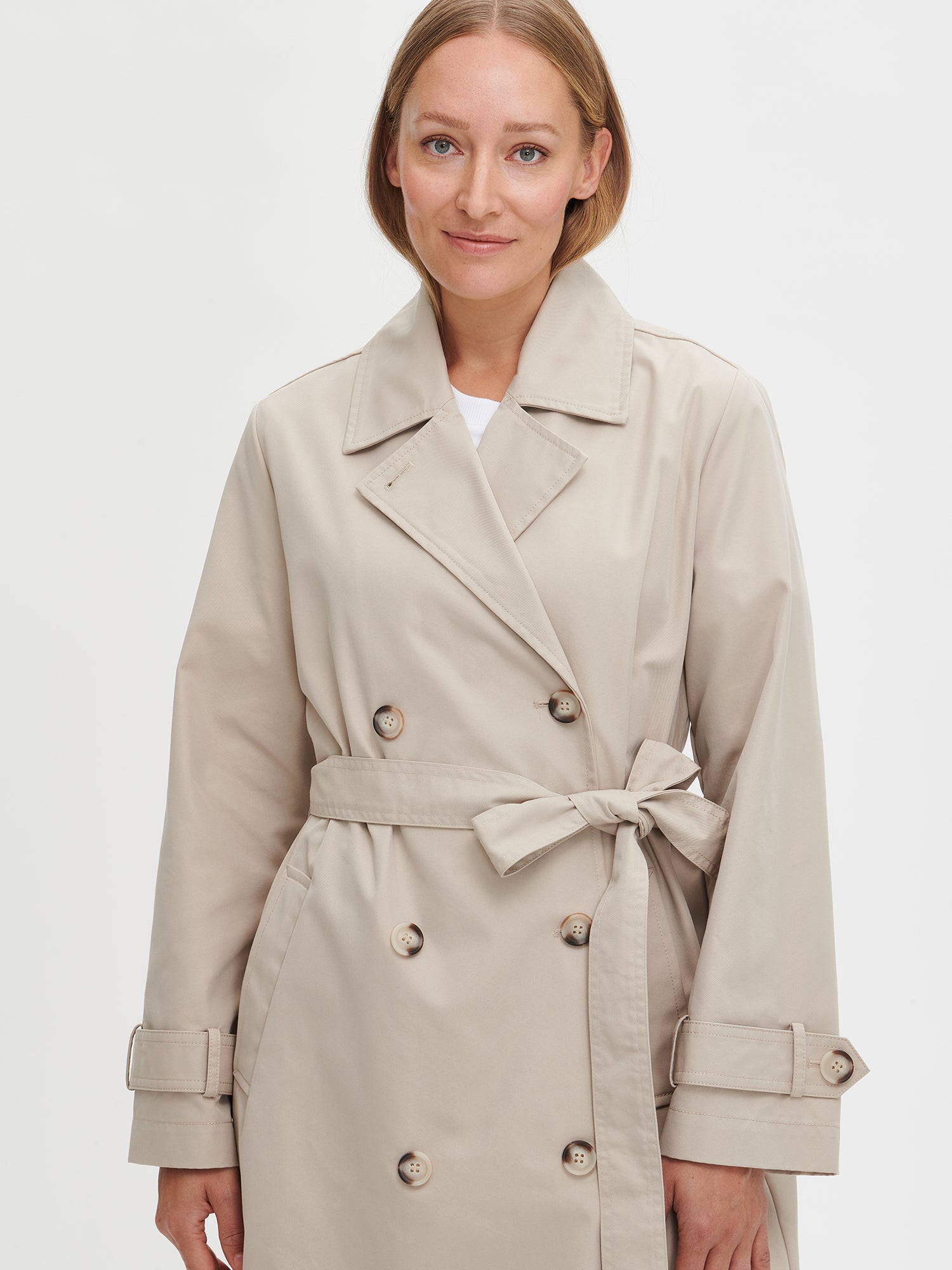 A timeless Beige trench coat on a model close up.