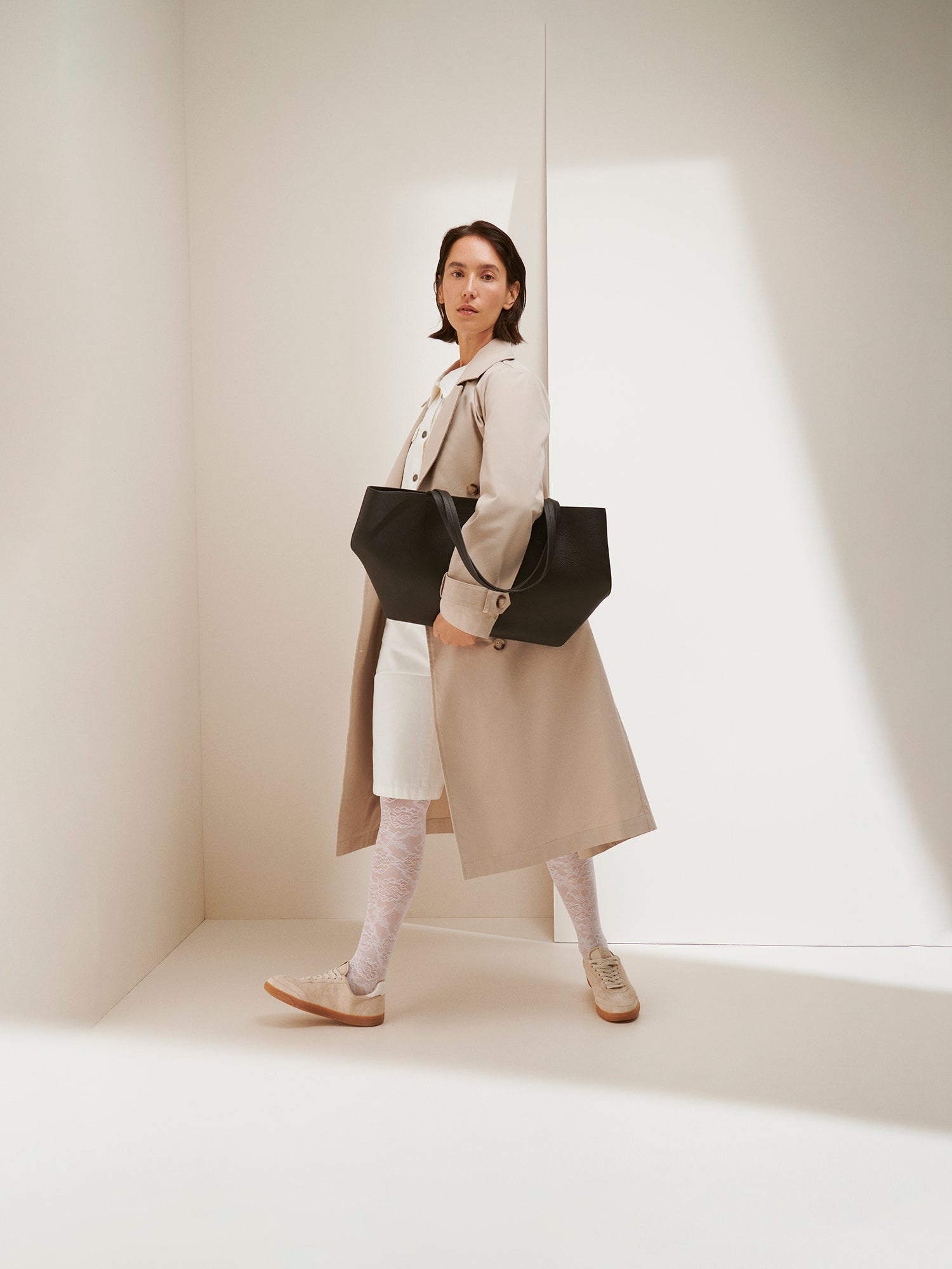 A timeless Beige trench coat on a model with a black bag