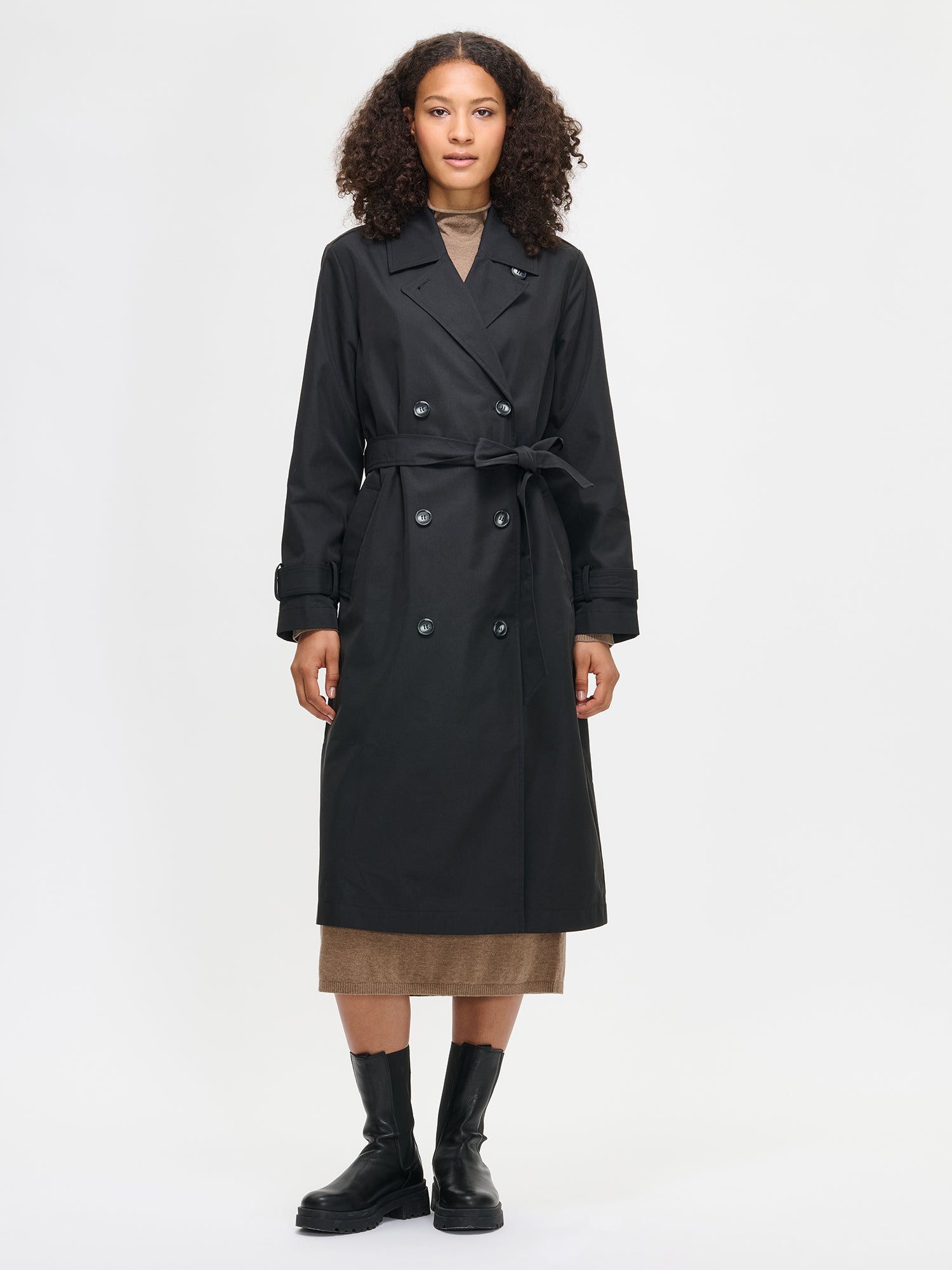 Woman wearing a black trench coat on a white background