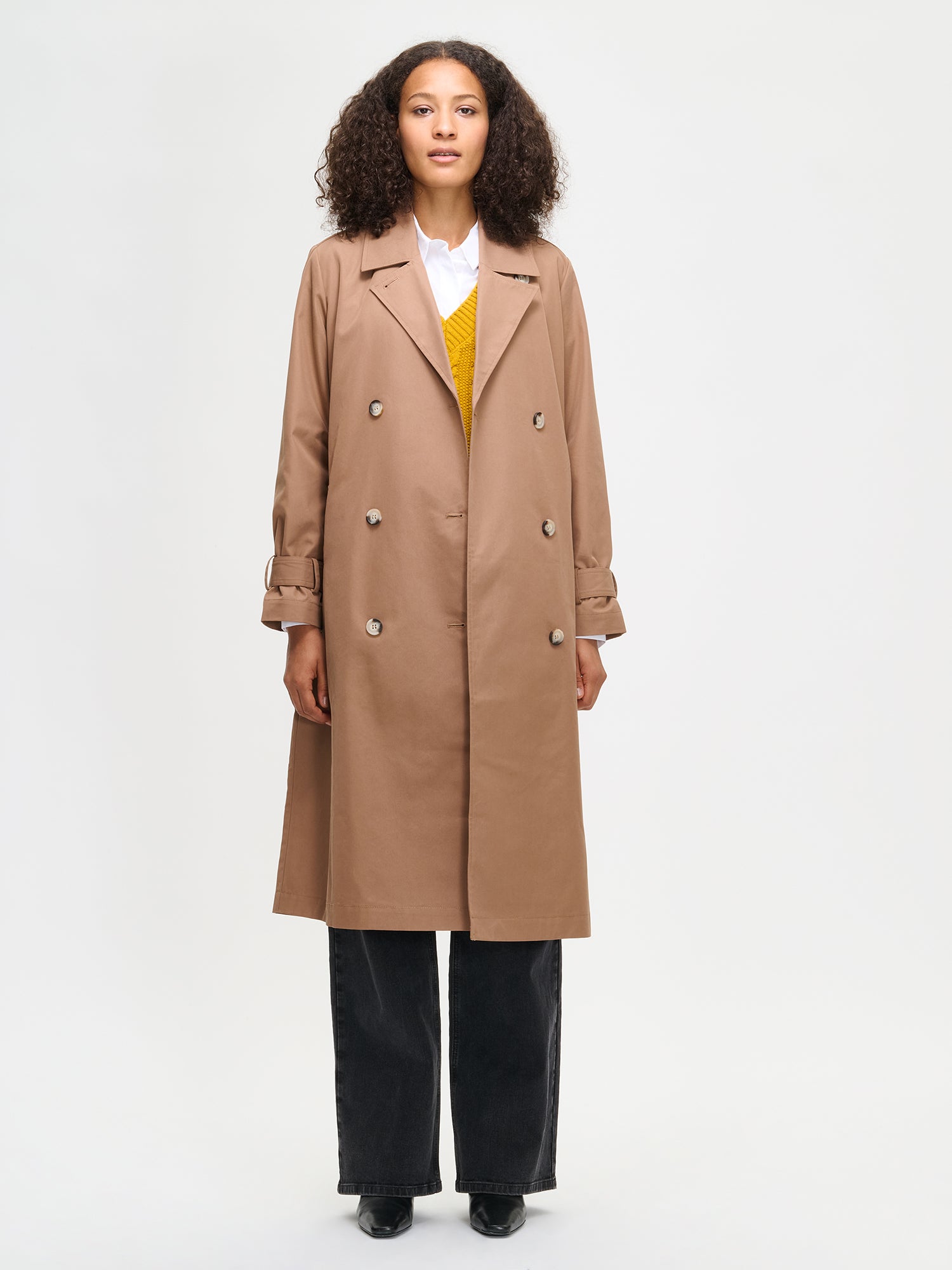 Woman wearing a brown trench coat on a white background