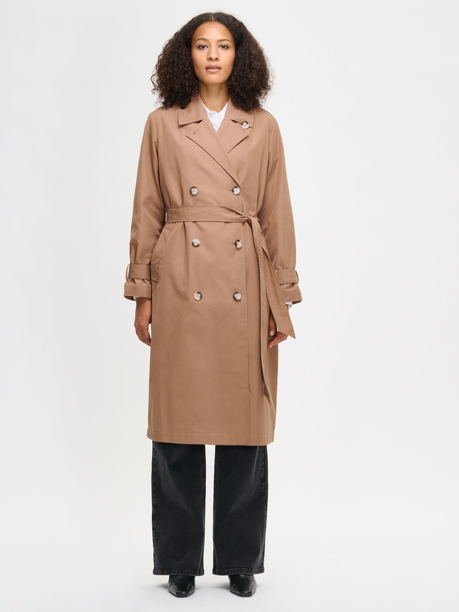 Woman wearing a brown trench coat on a white background
