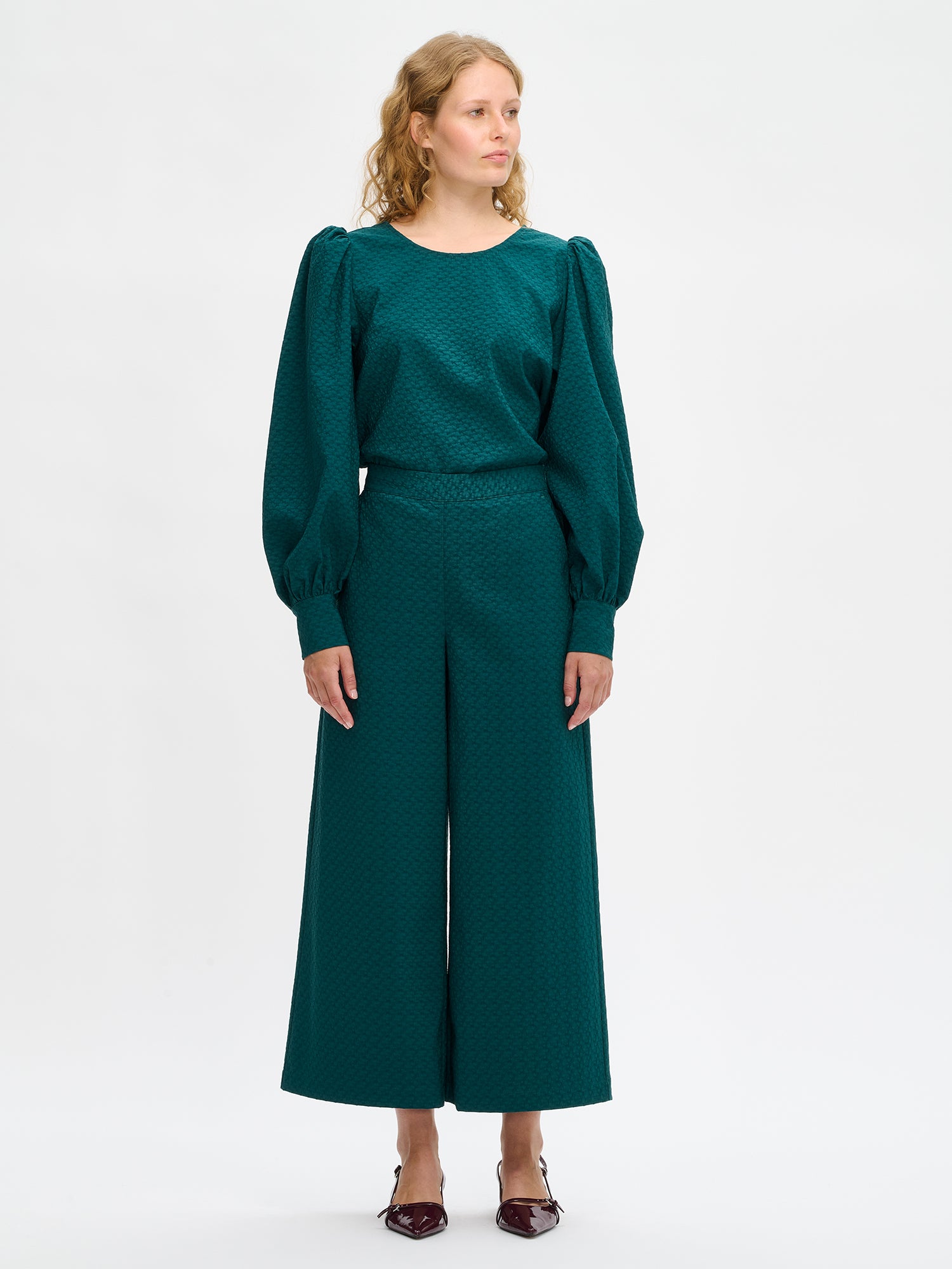 Nanso's elegant dark green Reliefi trousers for women feature a stylish textured pattern, perfect for both casual and formal occasions. Image from the front.