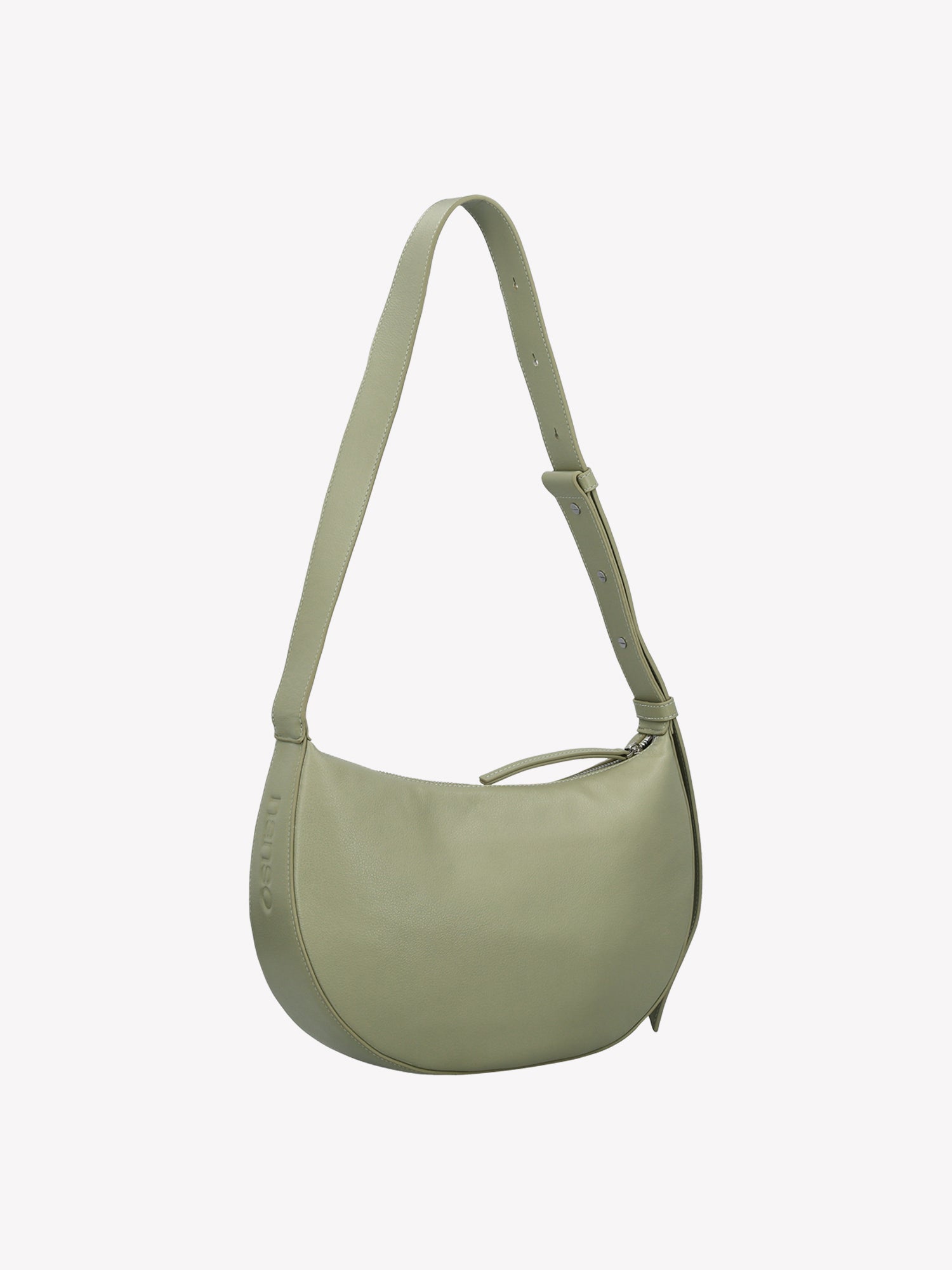 Nanso OLKA KUU - half moon-shaped leather shoulder bag in light green. Crafted with a sleek silhouette and practical zip closure and a comfortable shoulder strap. Product picture from the side angle.