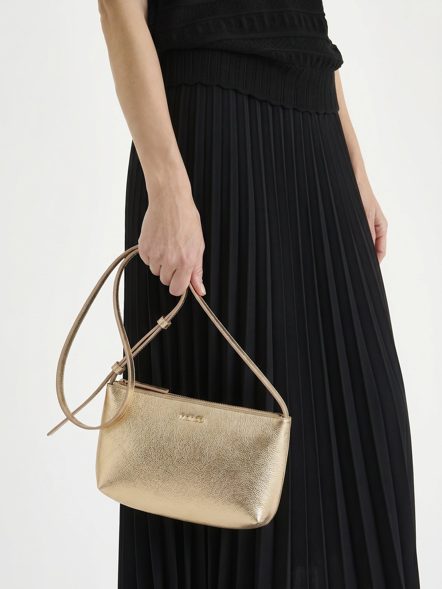 Nanso sleek Naru leather bag in gold pictured with a model in black outfit
