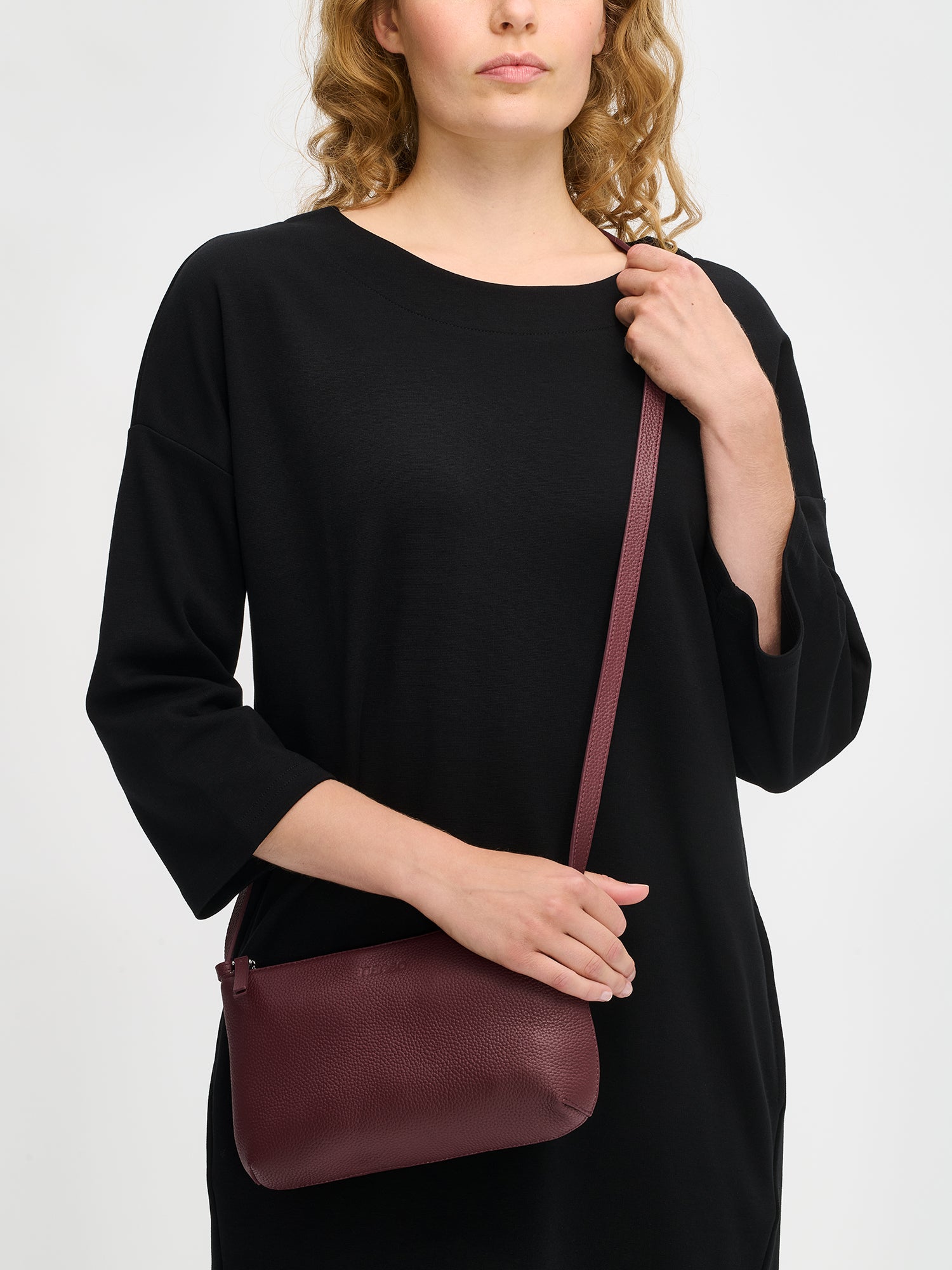 Nanso sleek burgundy Naru leather bag comes with a long, adjustable shoulder strap and a secure zip closure, on a model