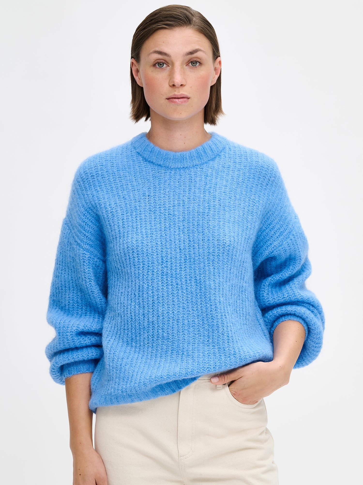 KARAMELLI women's luxurious mohair blend Knit Sweater in blue shade features a round neckline and full-length sleeves. Pictured on a model with jeans, close up.