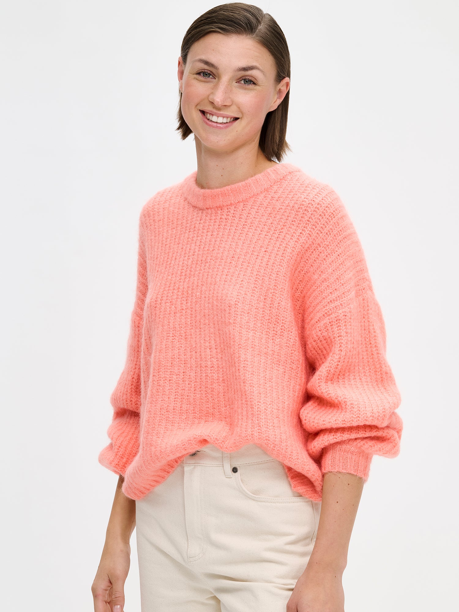 KARAMELLI women's luxurious mohair blend Knit Sweater in coral shade features a round neckline and full-length sleeves. On a model with jeans, close-up.
