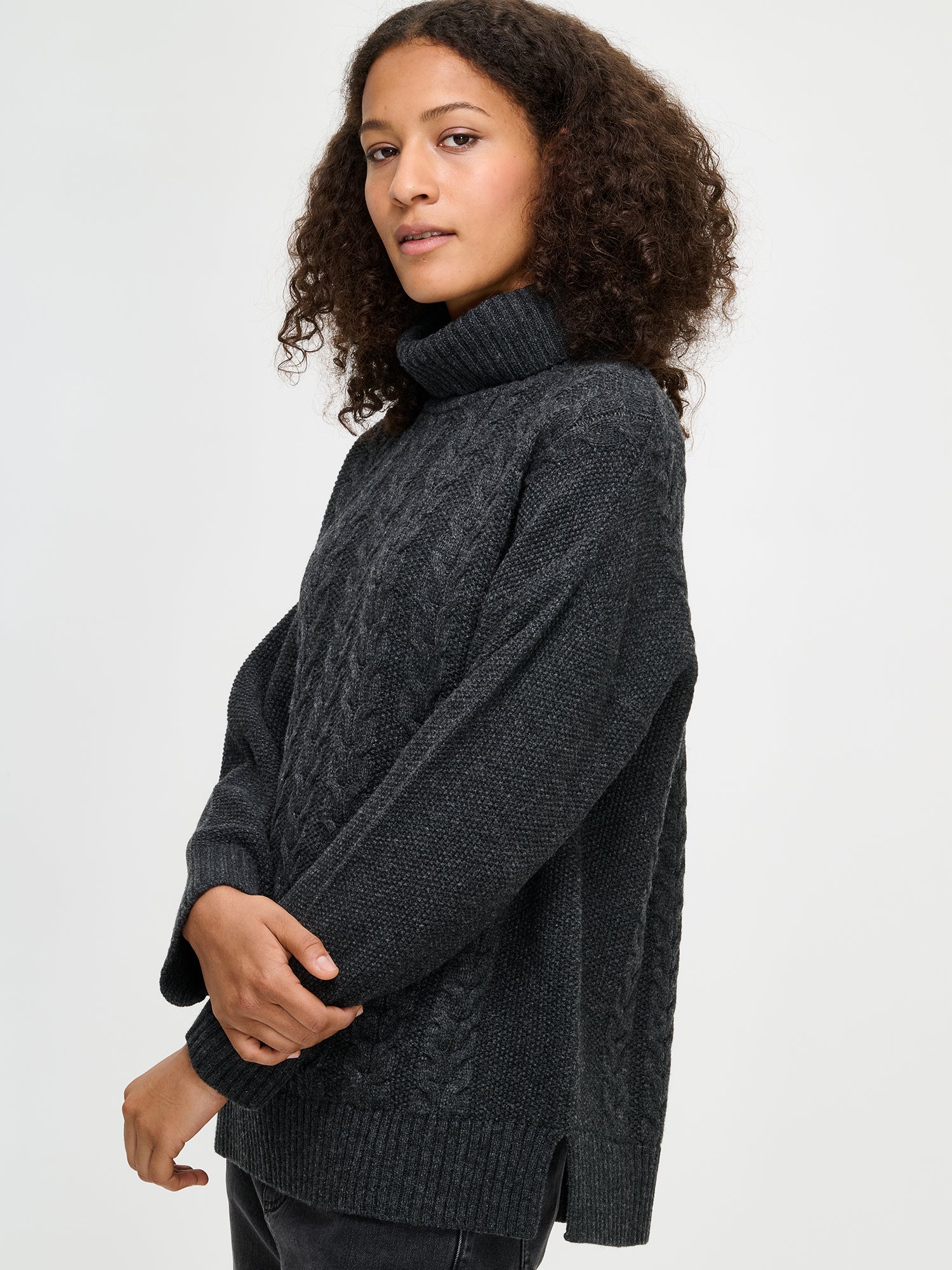 Woman wearing a dark gray cable knit sweater on a white background