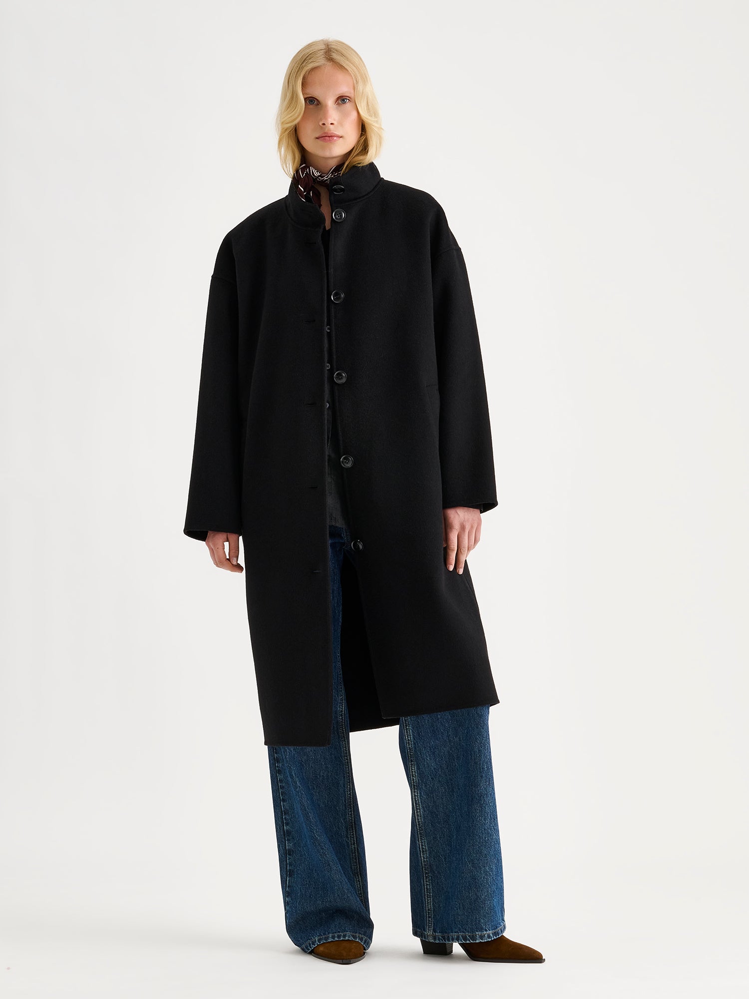 Nanso women's long black Elle wool coat on a blonde model with blue jeans.