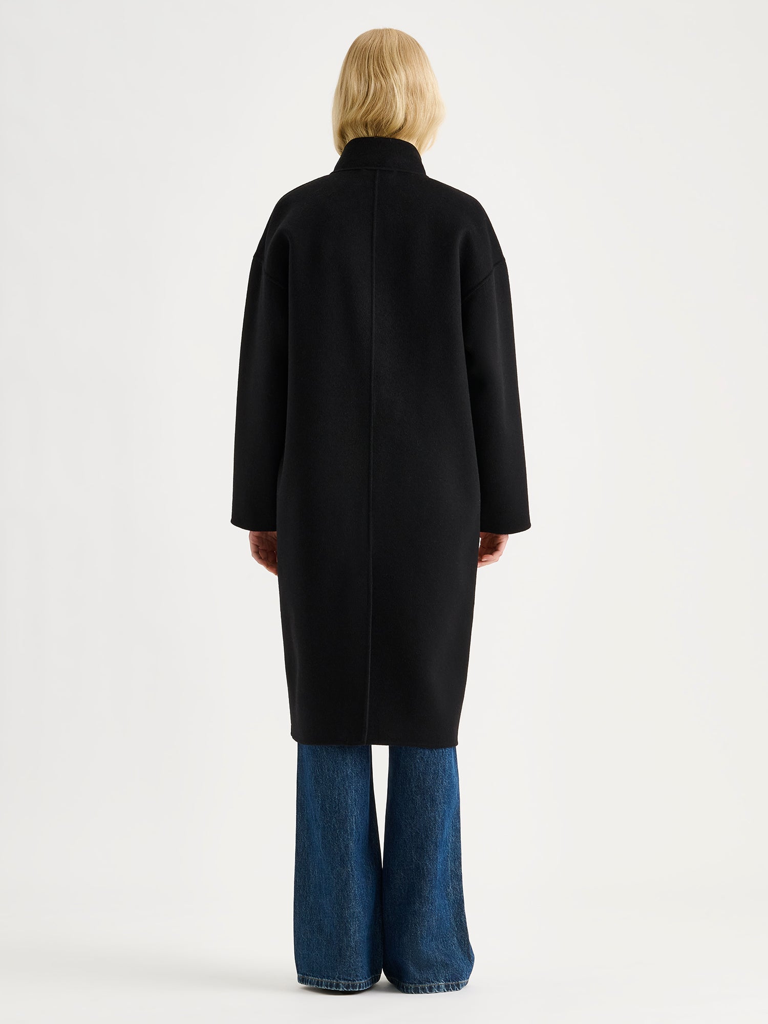 Nanso women's long black Elle wool coat on a blonde model with blue jeans, from the backside.