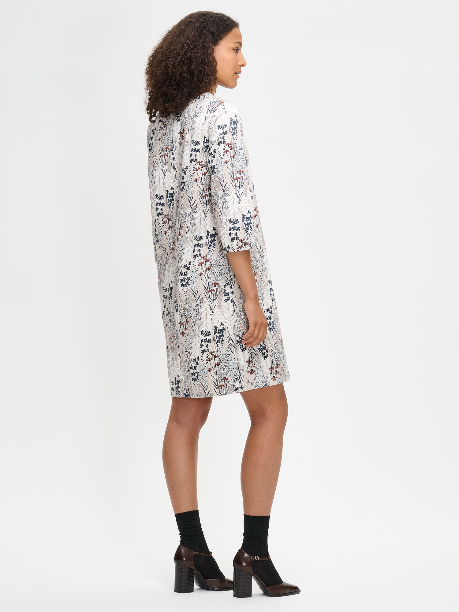 Women's Kuutamo dress in neutral color. Worn by a model, from the side.