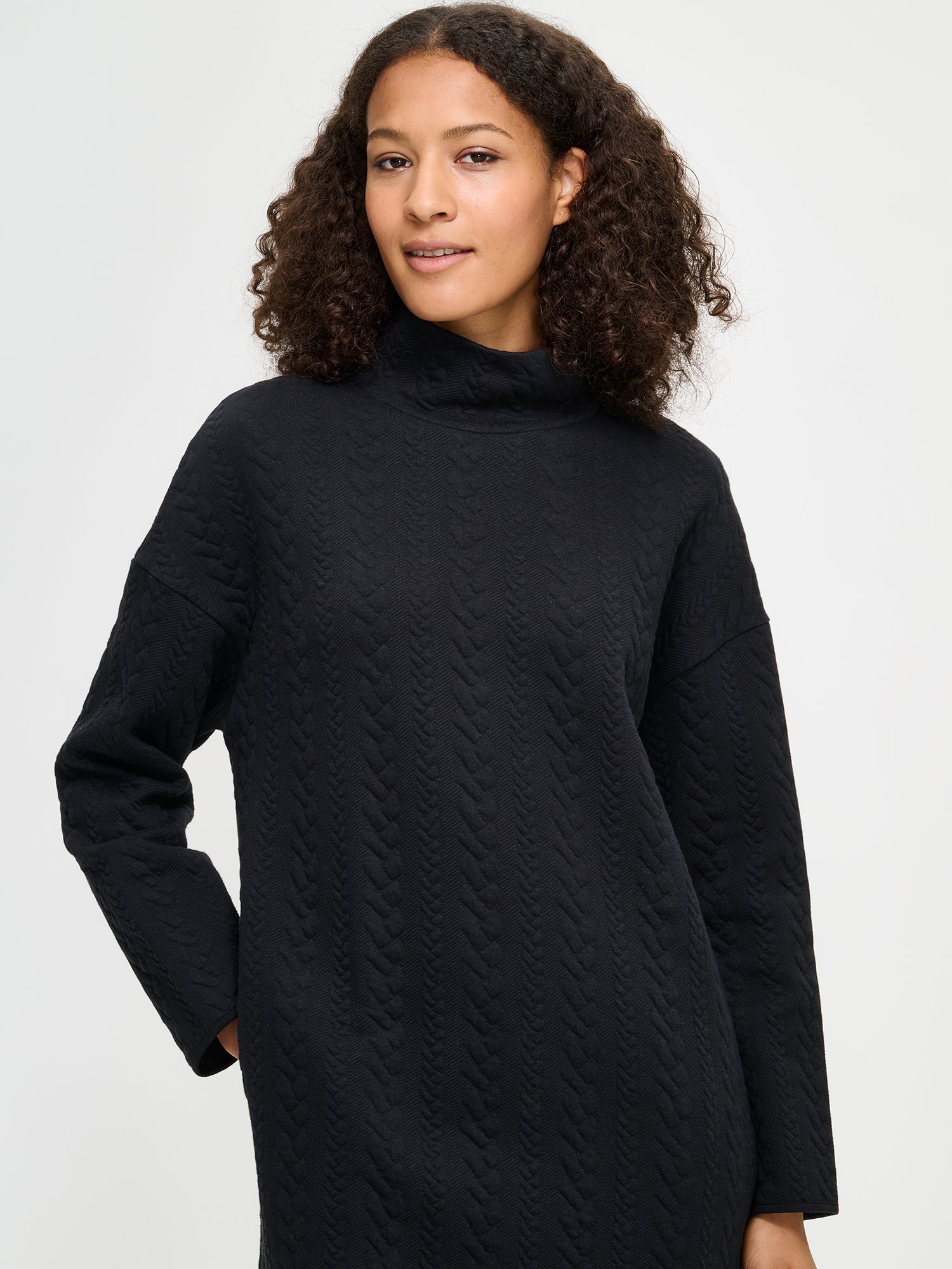 Woman wearing a black turtleneck dress against a white background