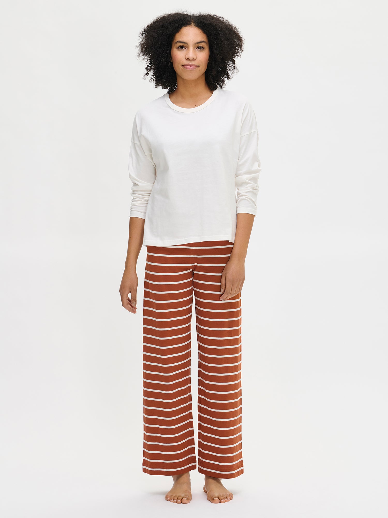 The Duetto shirt in off-white combined with the Duetto pants in brown and white on a model in the picture.