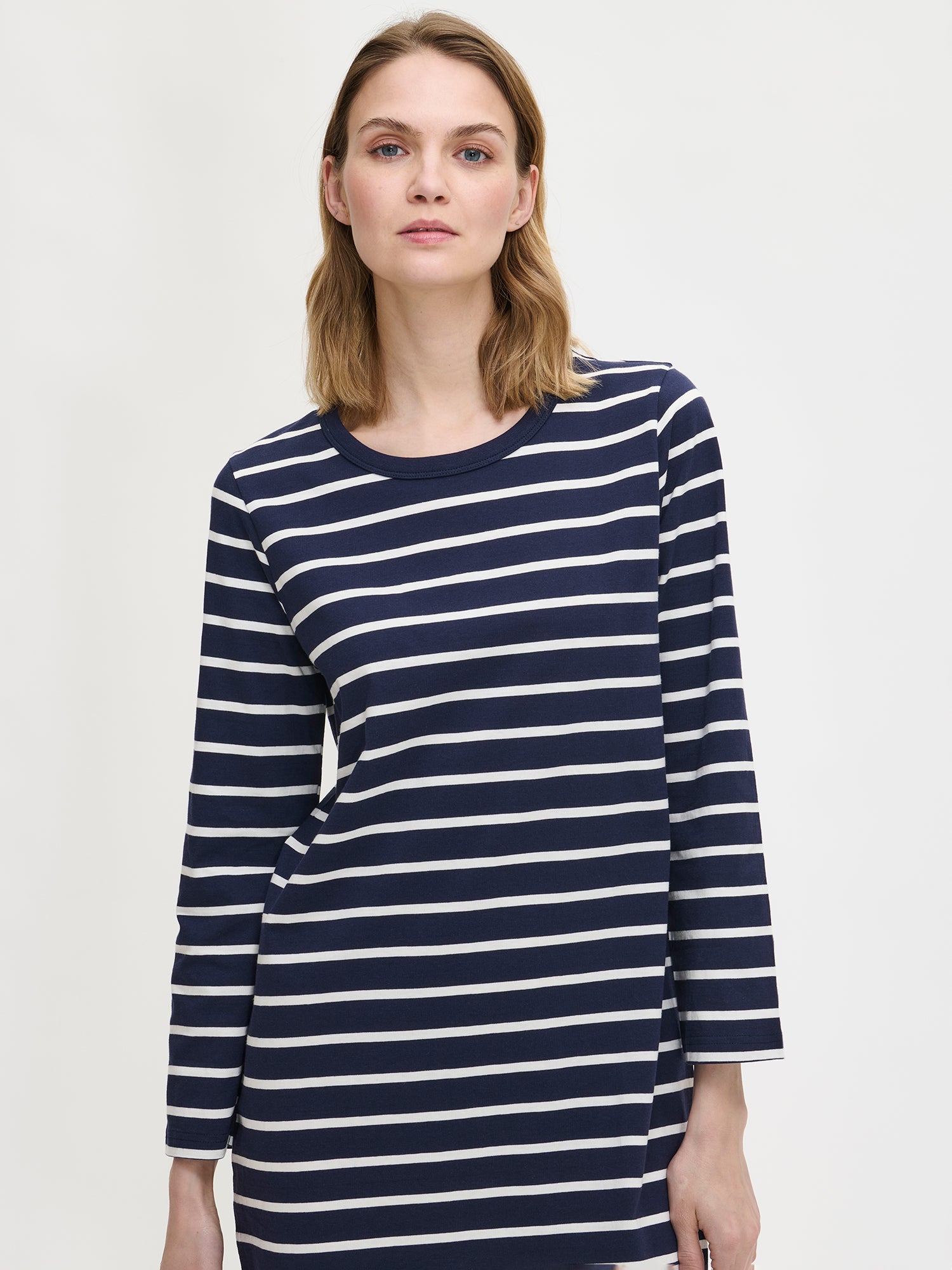 Women’s nightgown Duetto with blue and white stripes has long sleeves and a round neckline. The nightgown is worn by a model in a close-up picture.