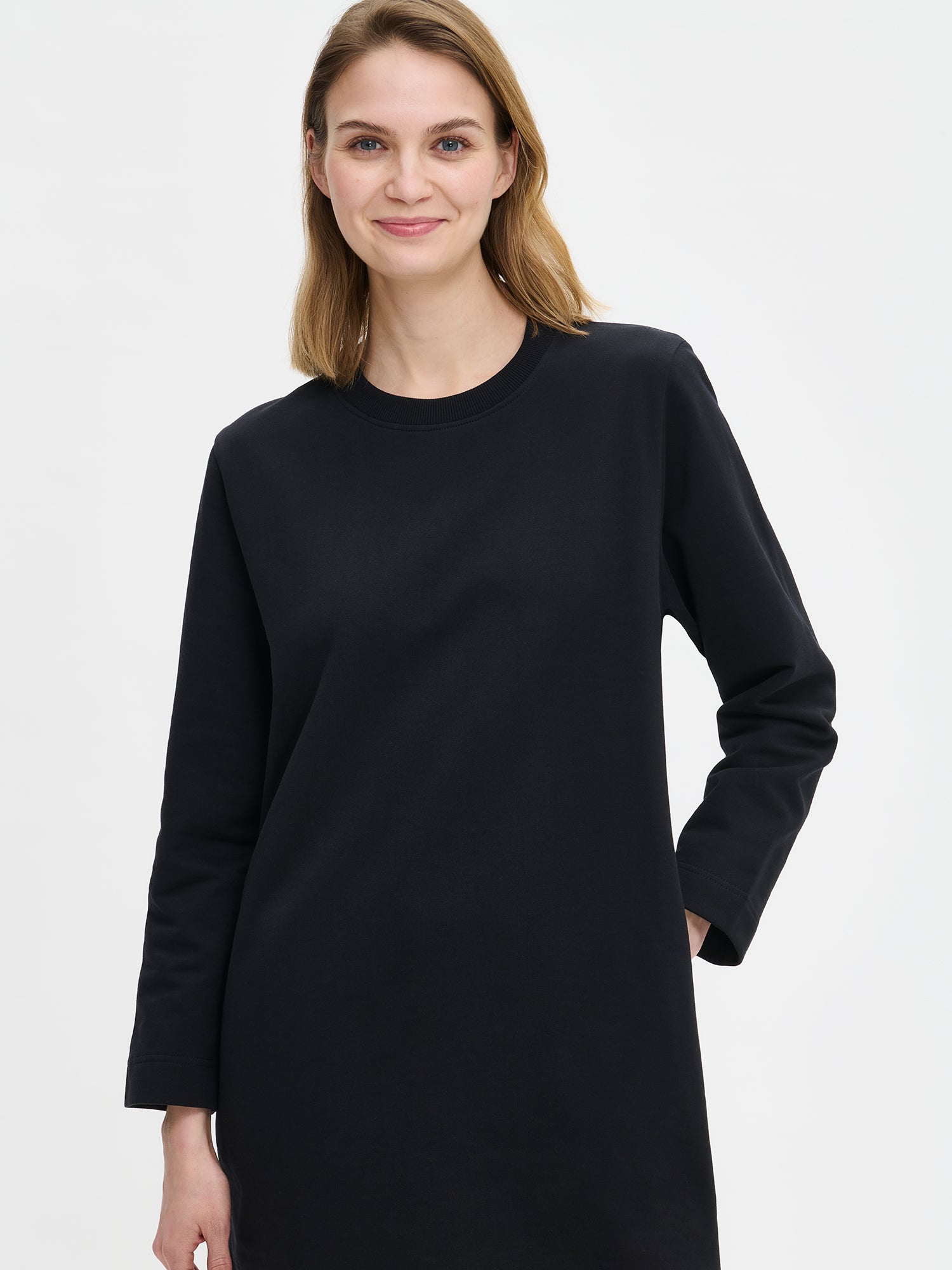 Koto dress features a round neckline, dropped full-length sleeves and side pockets. Here Koto dress on a model in a close-up picture.