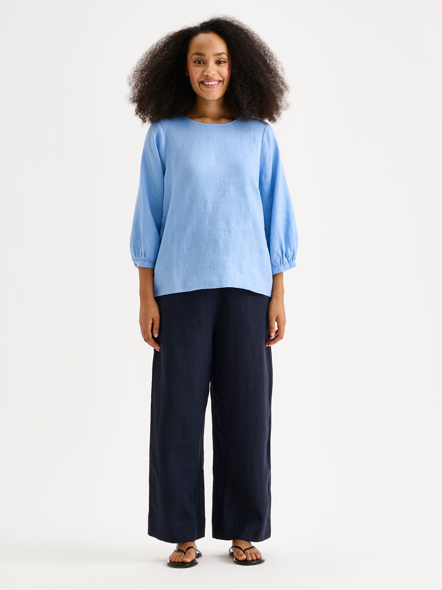 Nanso women's Saralia linen Blouse in blue on a model with dark blue linen trousers.