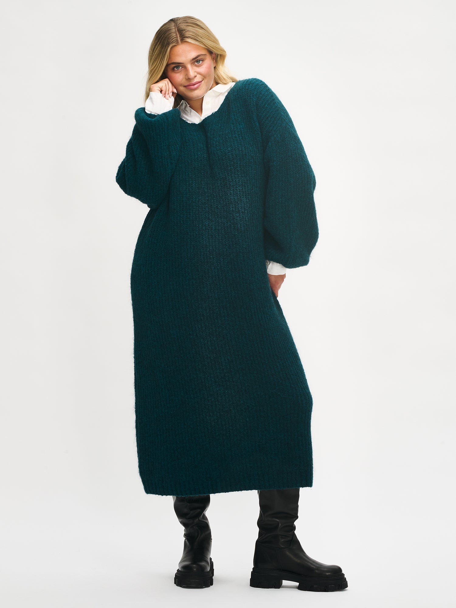 Woman wearing a long green Karamelle knit sweater dress on a white background