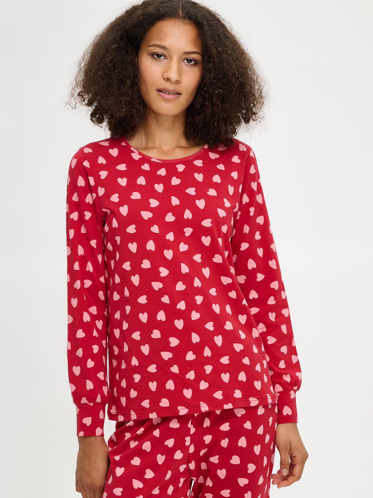 Nanso women's Amor red pyjamas with a joyful patterned design, round neckline and long sleeves, on a model from the front, close-up.