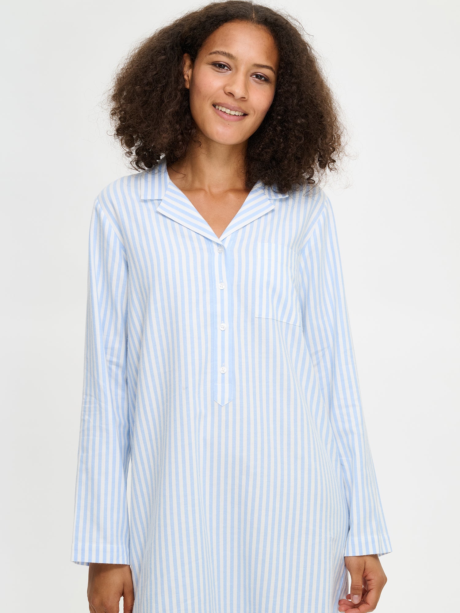 The light blue nightgown features long sleeves, a beautifully shaped collar, a button stand, and a rounded hem. Here on a model in a close-up picture.