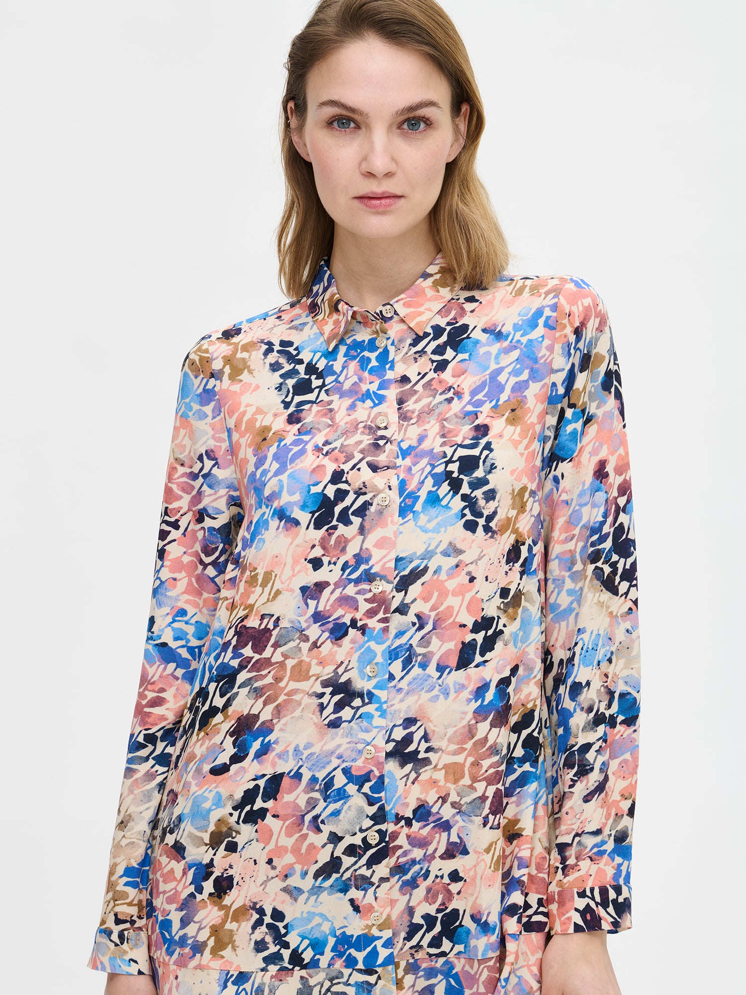 Women's SAGITTA Dress with vibrant pattern and flared hem. The dress features a front button closure and timeless collar design, paired with full-length sleeves. Pictured on a model, close-up.