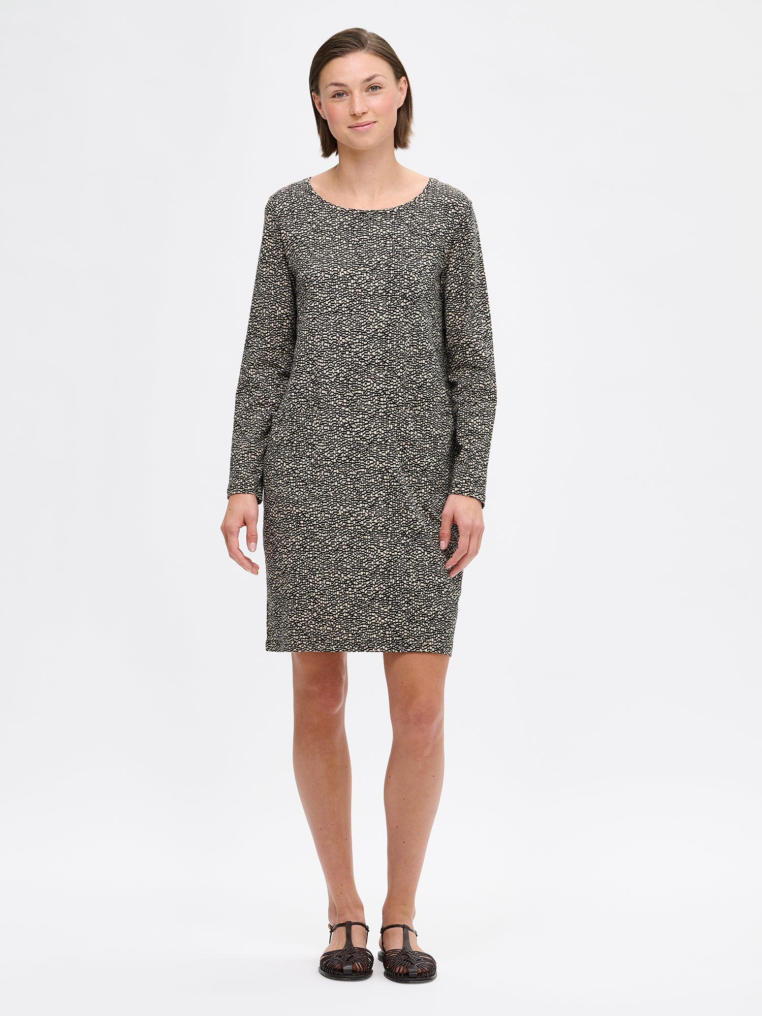 Nanso women's patterned Kaislat dress. The dress features a round neckline and full-length sleeves. The dress has hidden pockets in the seam. On a model with sandals.
