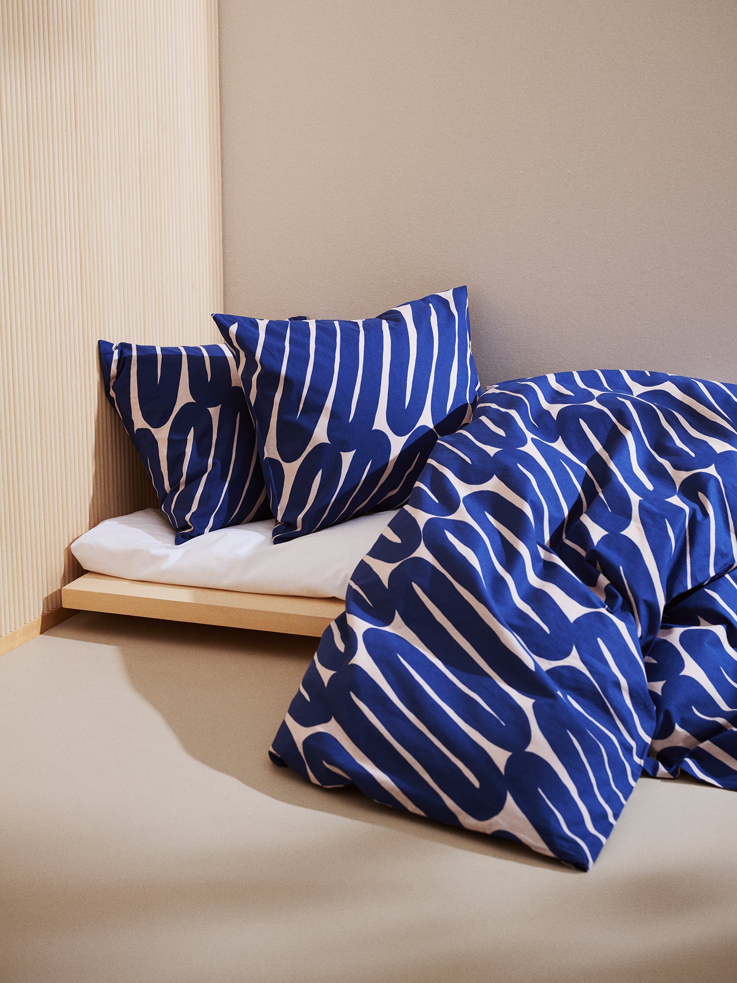 Laskos duvet cover set in bed setting combined with a white sheet in a beige room.