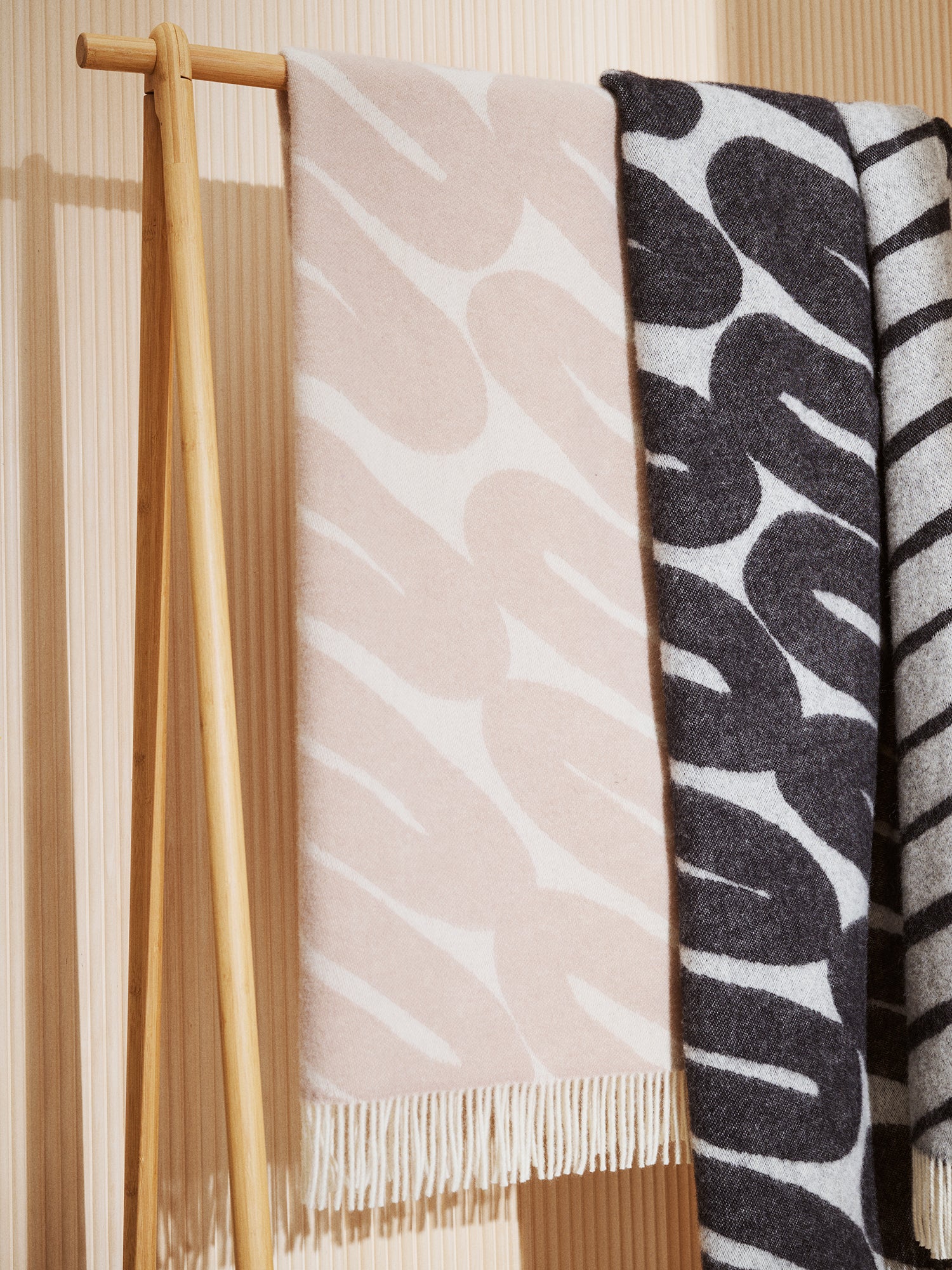 Laskos wool blanket in black and beige with lighter color graphic pattern placed on a clothing rack.