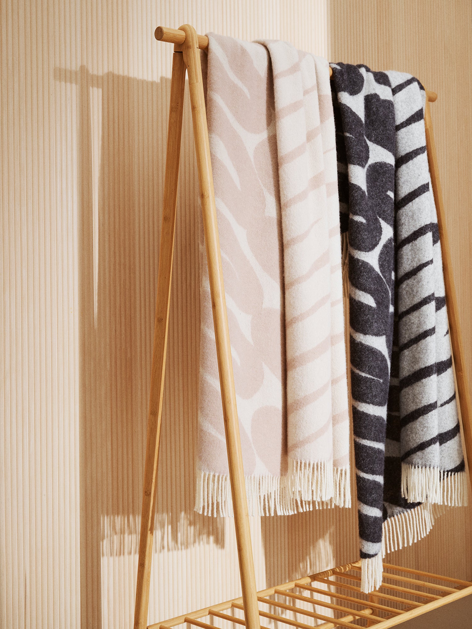 Laskos wool blanket in beige and black with lighter color graphic pattern placed on a clothing rack.