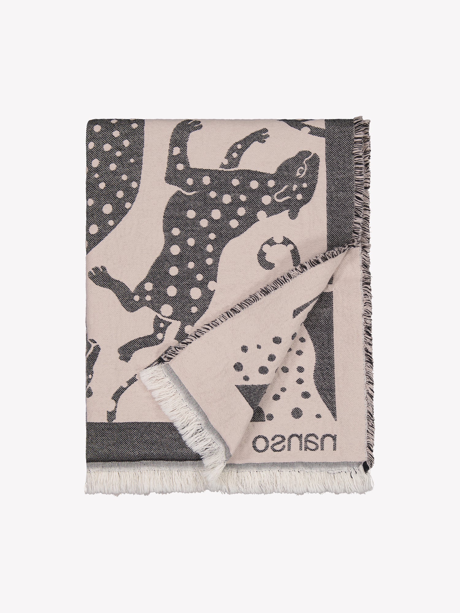 The light pink Leonora blanket with grey leopards closed in a product picture. The blanket has fringed edges and embroidered Nanso logo in the corner.